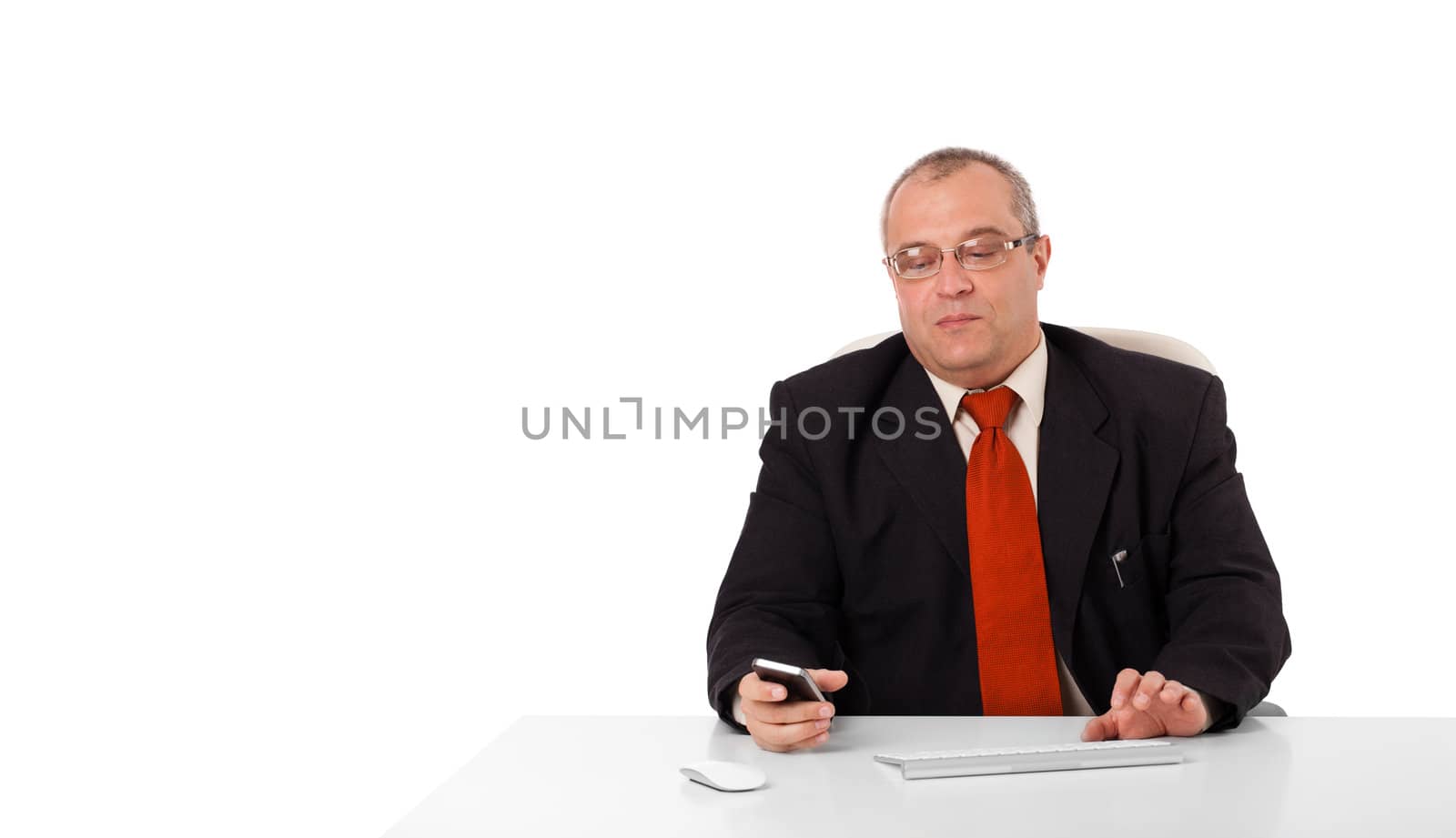 businessman sitting at desk and holding a mobilephone with copys pace, isolated on white