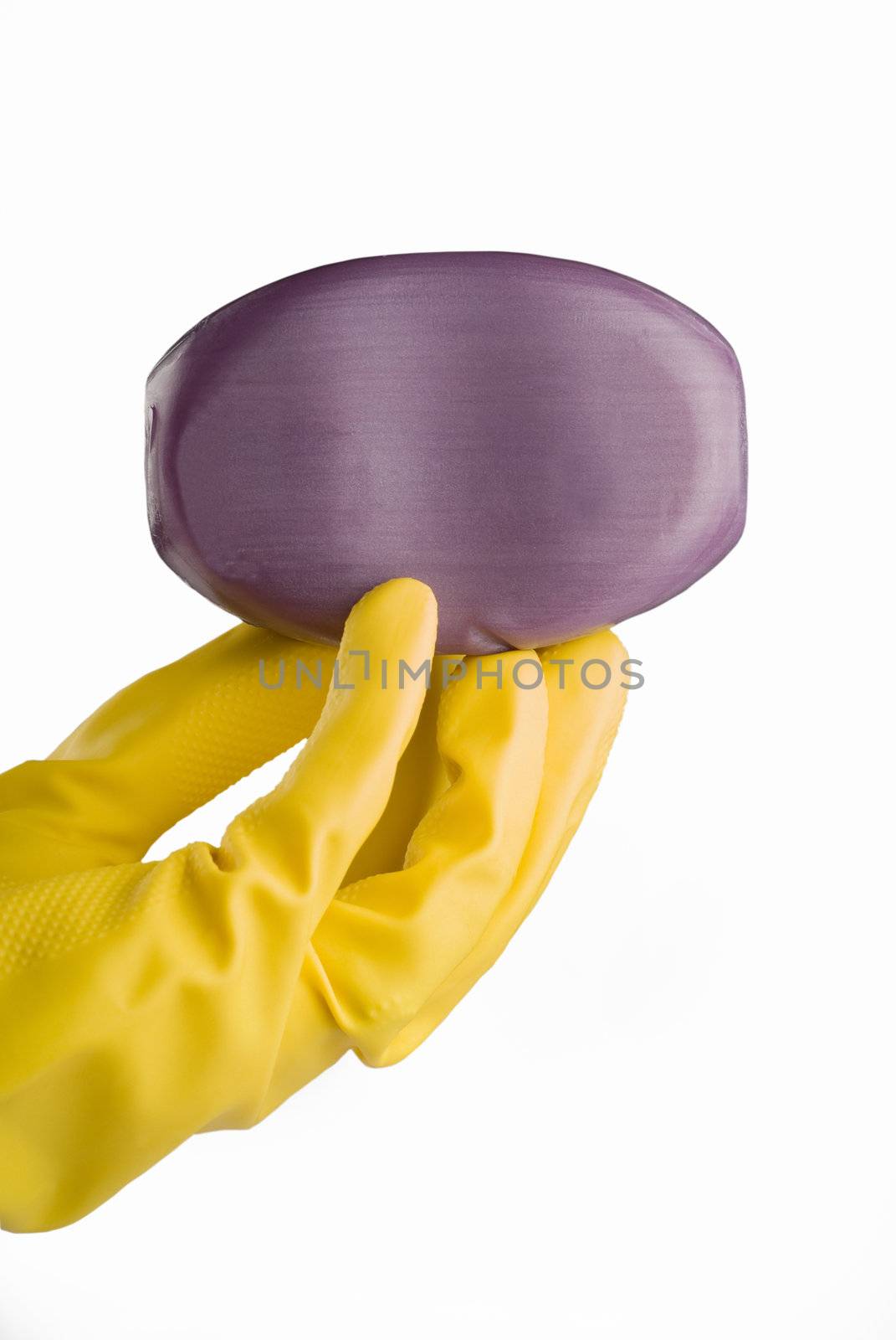 Hand in yellow protective utility glove holding purple or lavender bar of soap