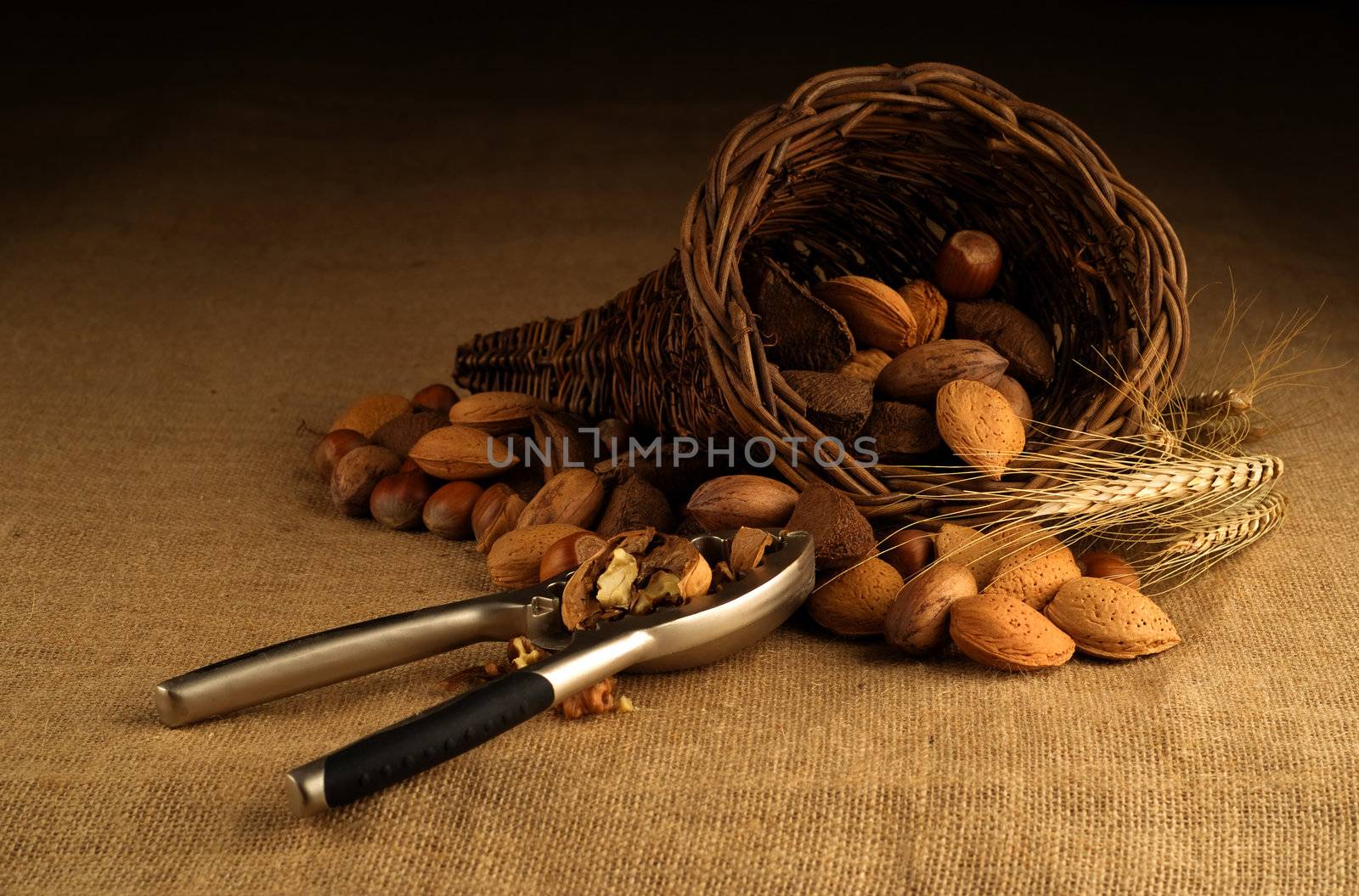Assortment of nuts displayed in basket with nutcracker on hesian background
