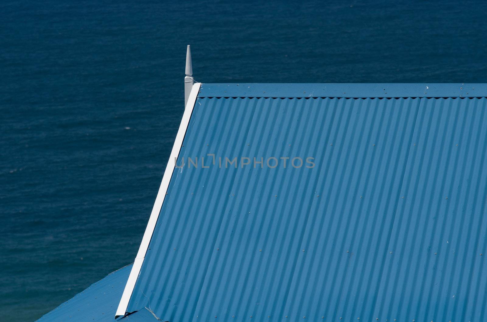 Roof of blue and white Mediteranean style holiday house with sea ocean in background