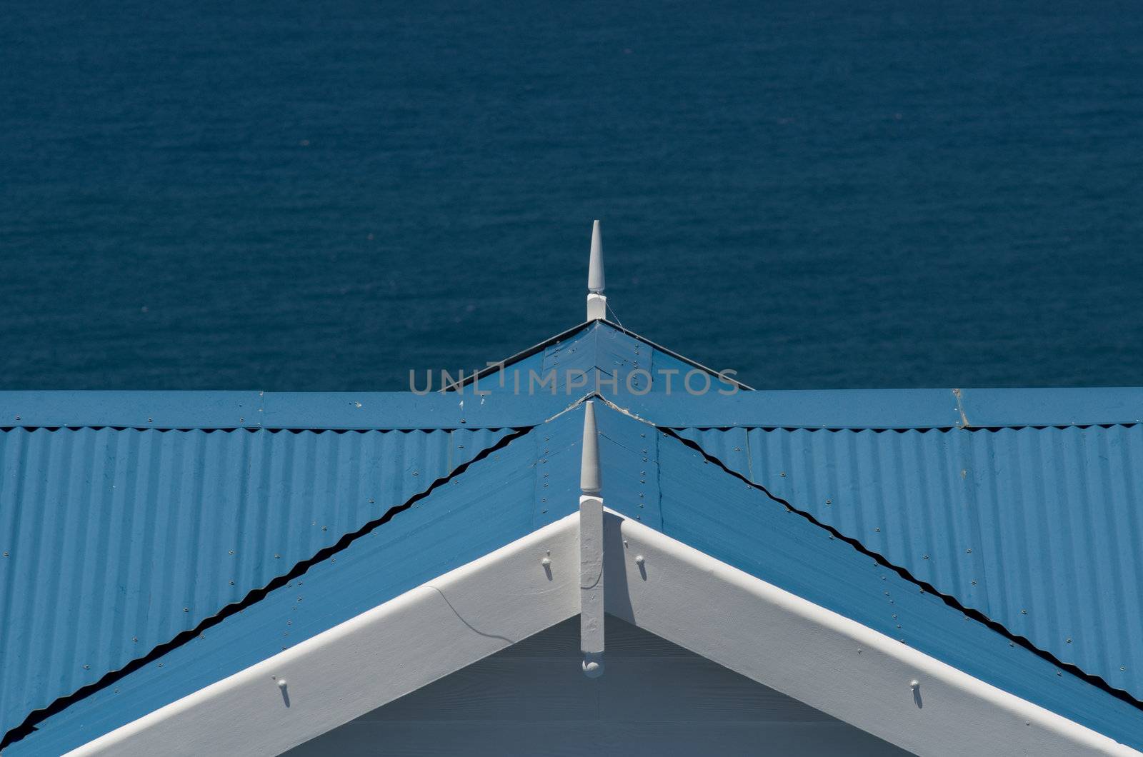 Blue and white Mediteranean style holiday house roof with sea ocean in background