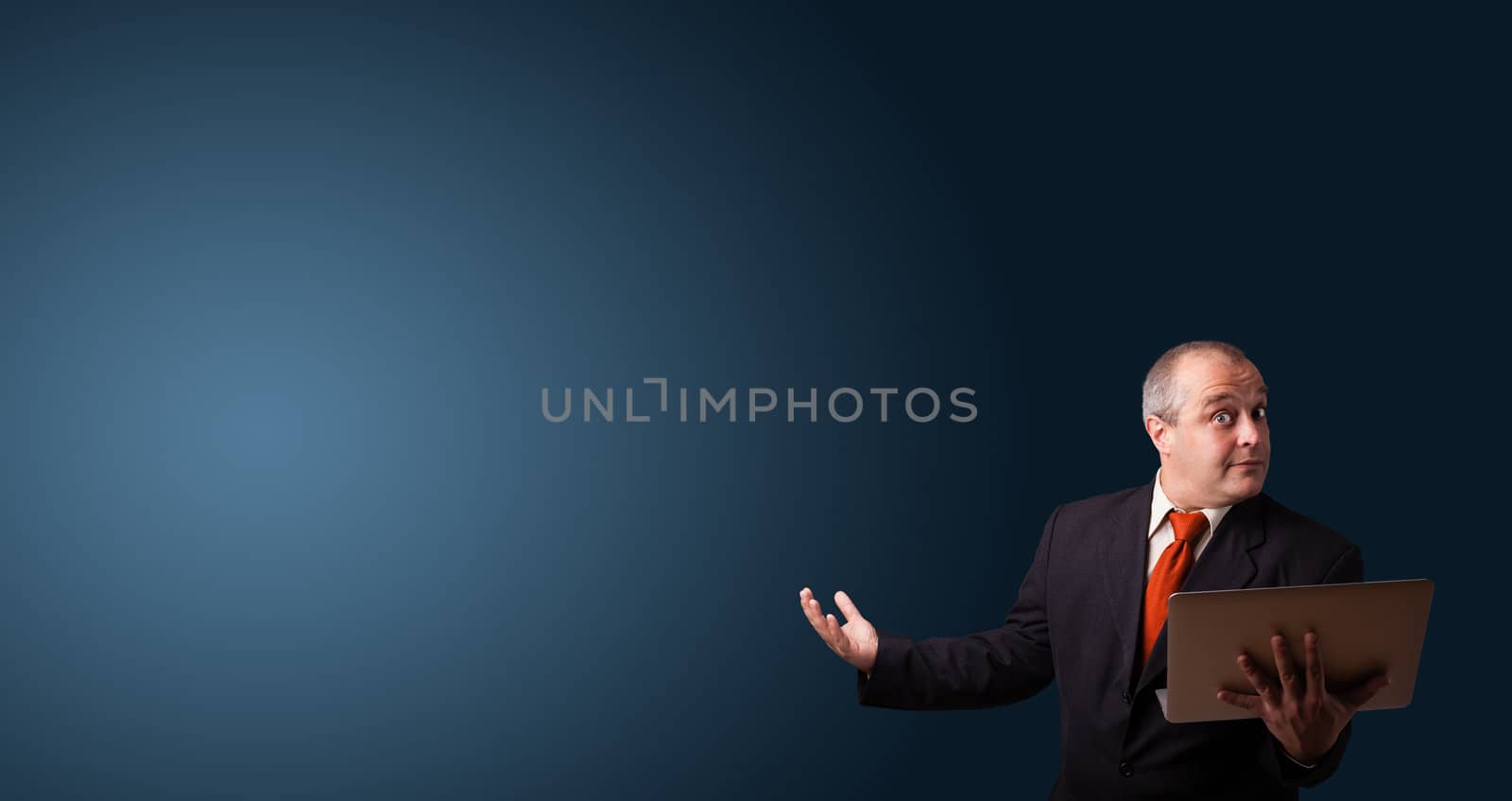 businessman in suit holding a laptop and presenting copy space