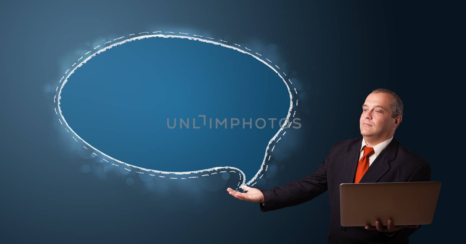 businessman in suit holding a laptop and presenting speech bubble copy space