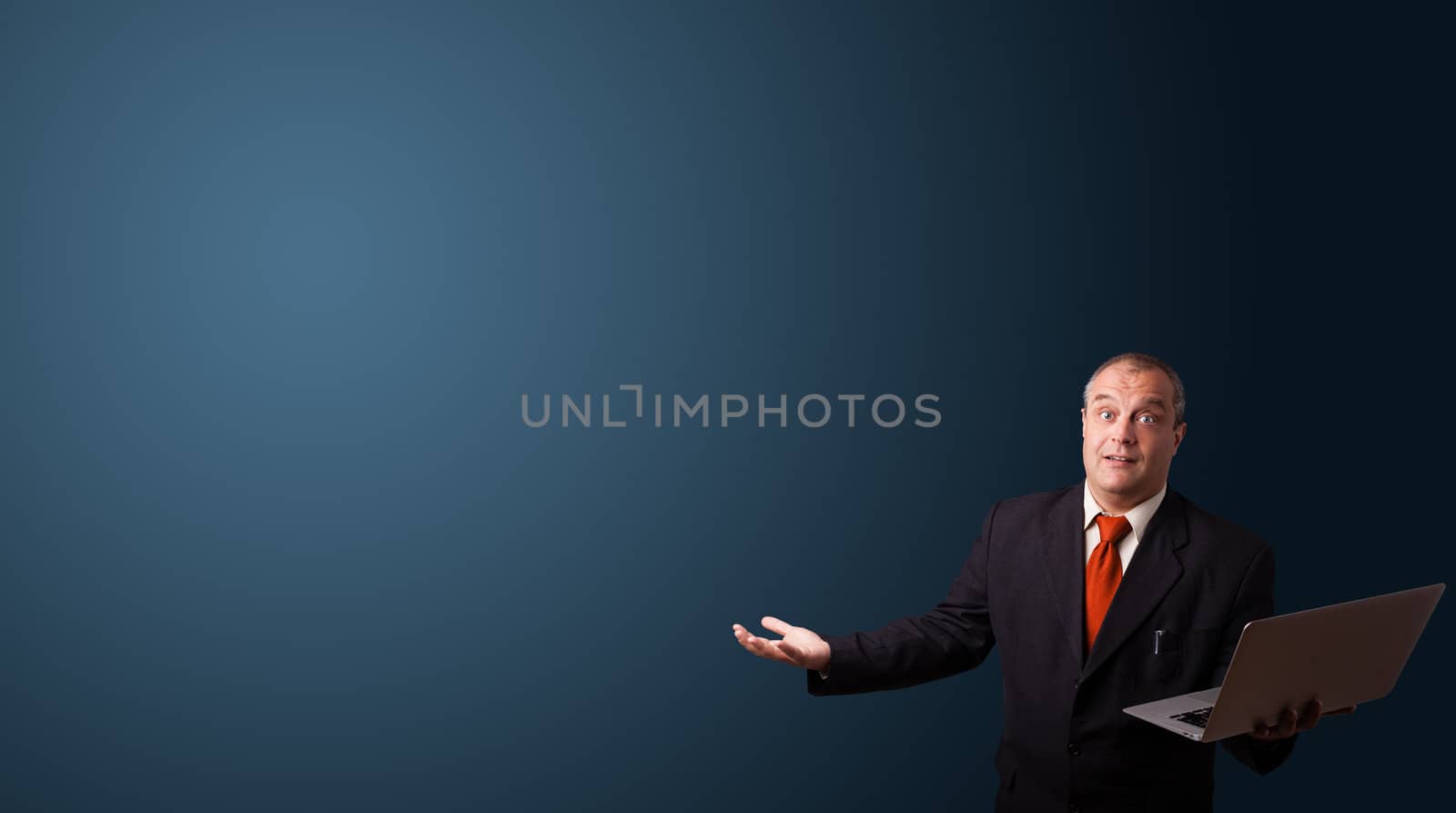 businessman in suit holding a laptop and presenting copy space