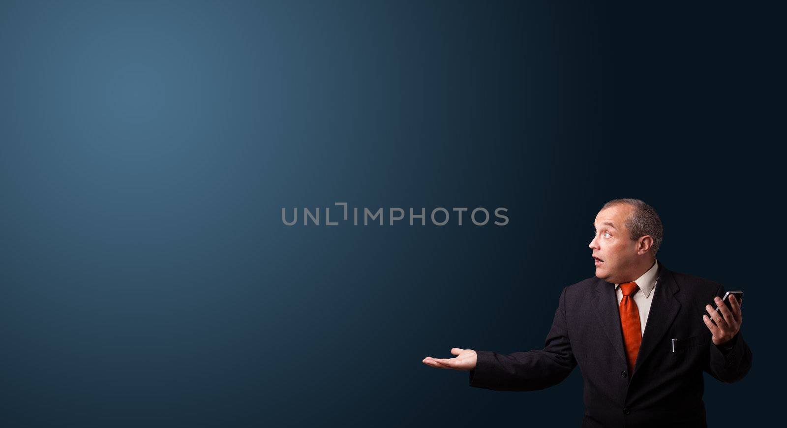 crazy businessman in suit holding a phone and presenting copy space