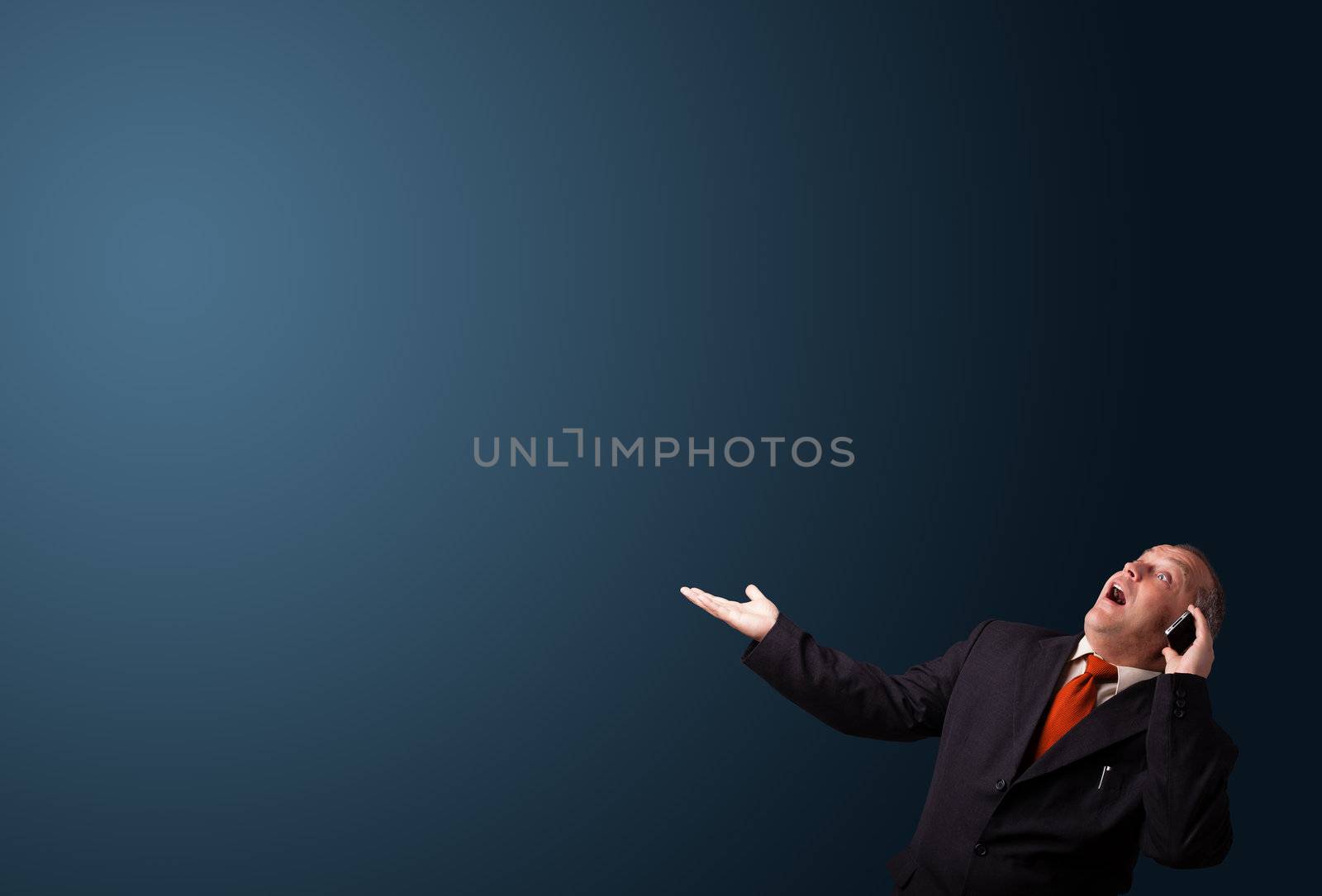 crazy businessman in suit holding a phone and presenting copy space