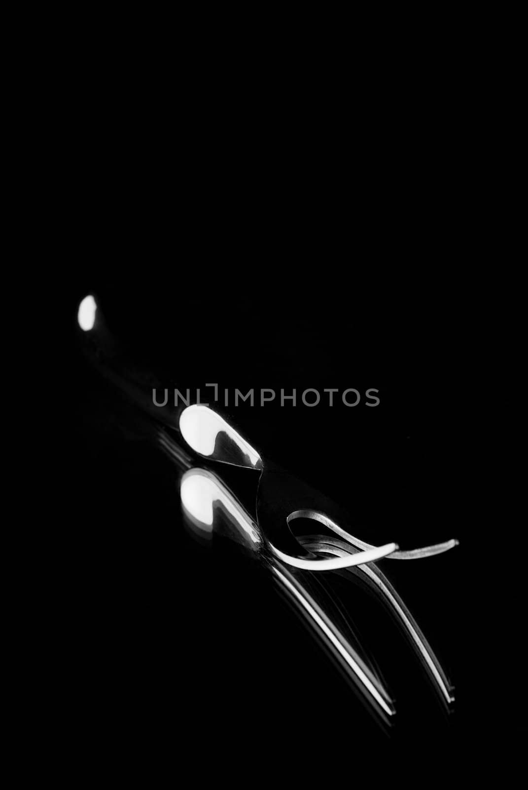 Single carving fork reflection on mirror with black background