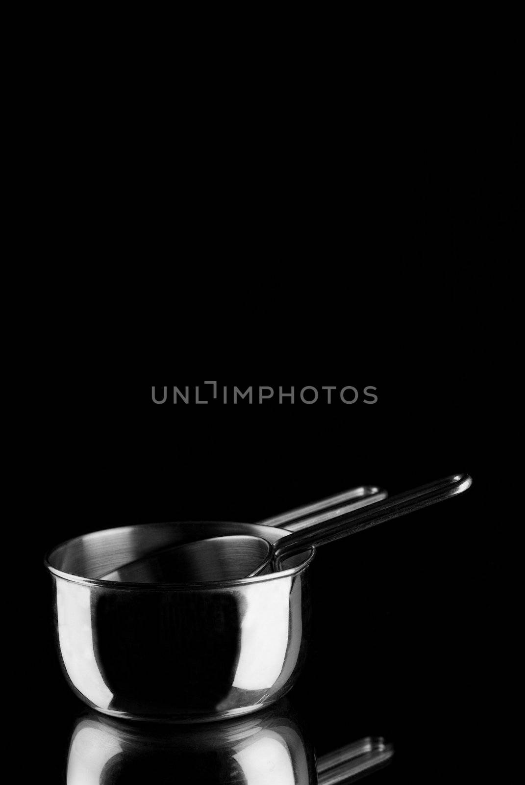 Stainless steel measuring cups on mirror with balck background