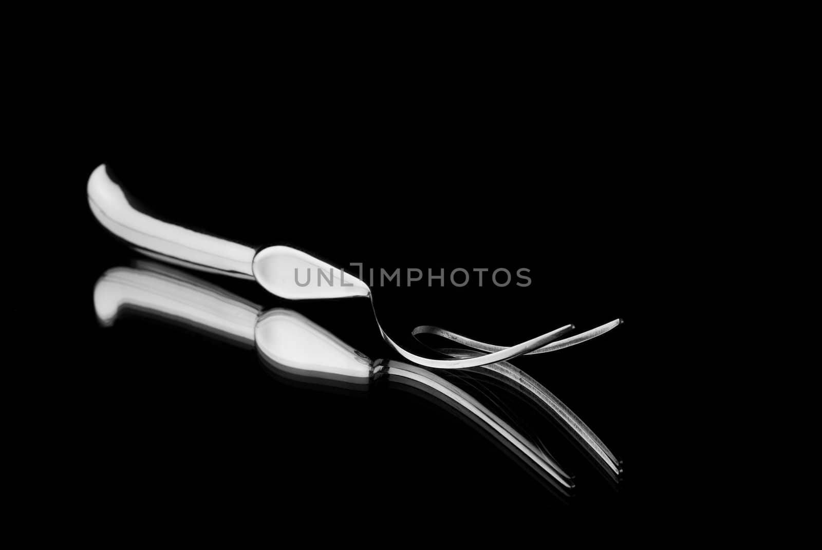 Single carving fork reflection on mirror with black background