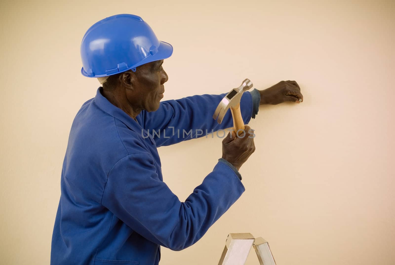 African American Construction Worker, Handyman, Carpenter, Standing on Ladder Working with Hammer