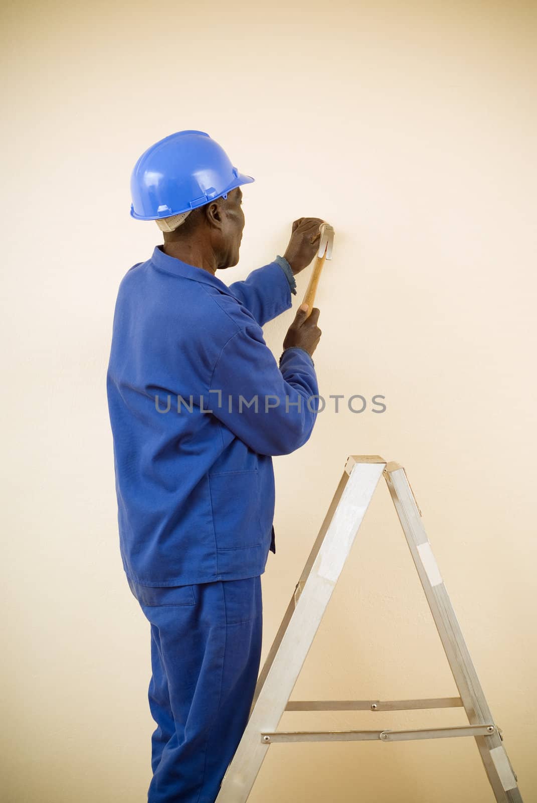 African American Construction Worker, Handyman, Carpenter, Standing on Ladder Working with Hammer