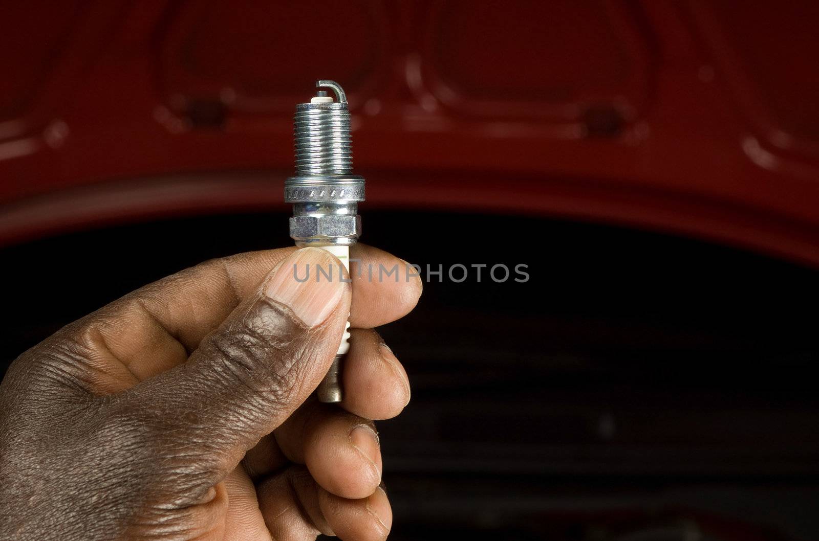 South African or American mechanic with spark plug and engine maintenance repair car background