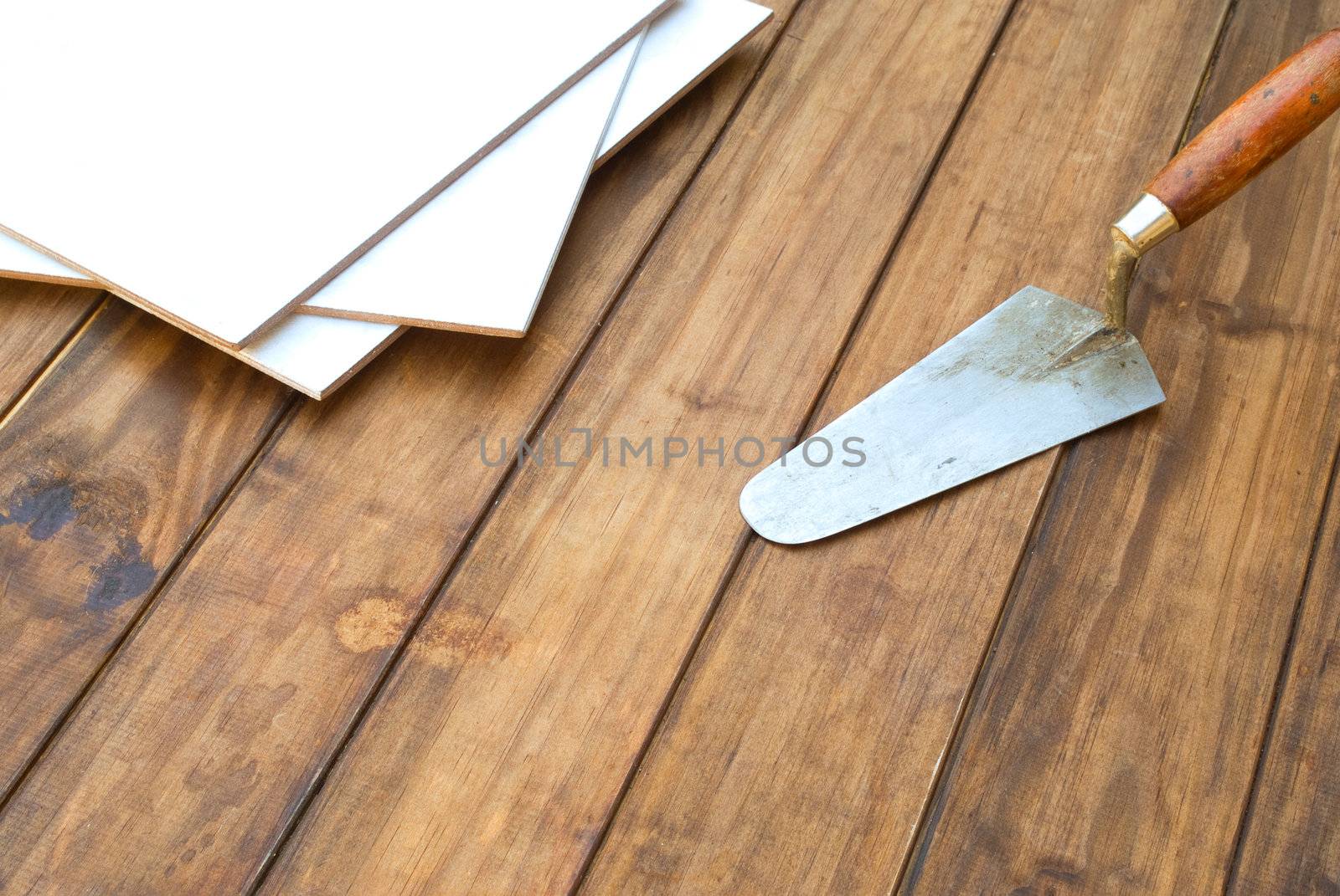 Home improvement floor tiles on wooden table with plaster tool - space for text