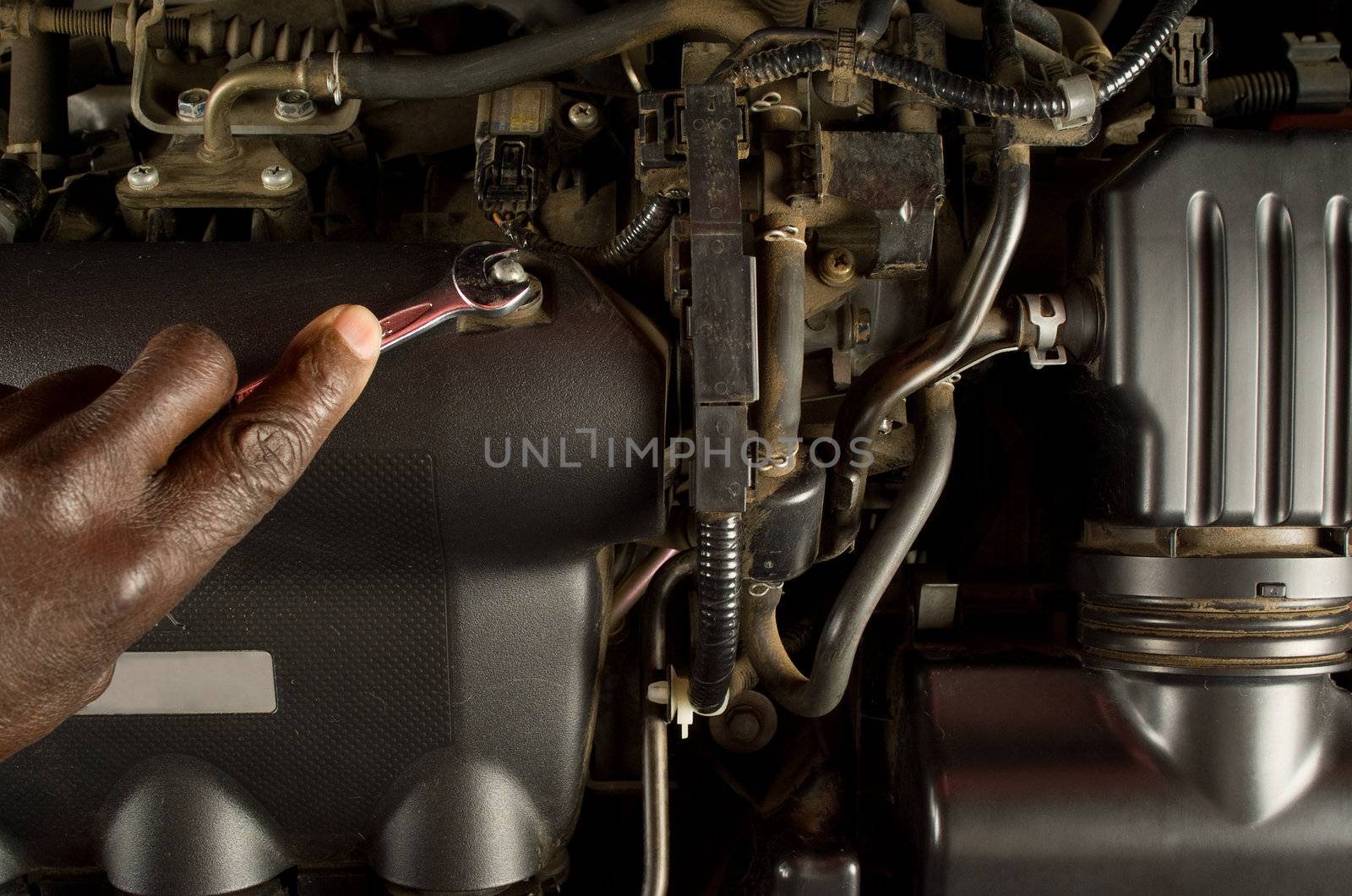 South African or American mechanic hand with spanner fixing or servicing car engine