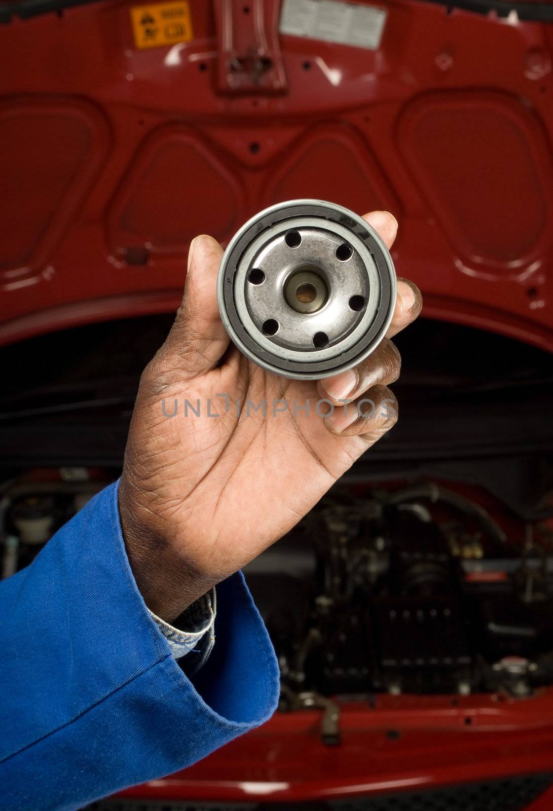 South African or American blue collar mechanic hand with oil filter service car maintenance