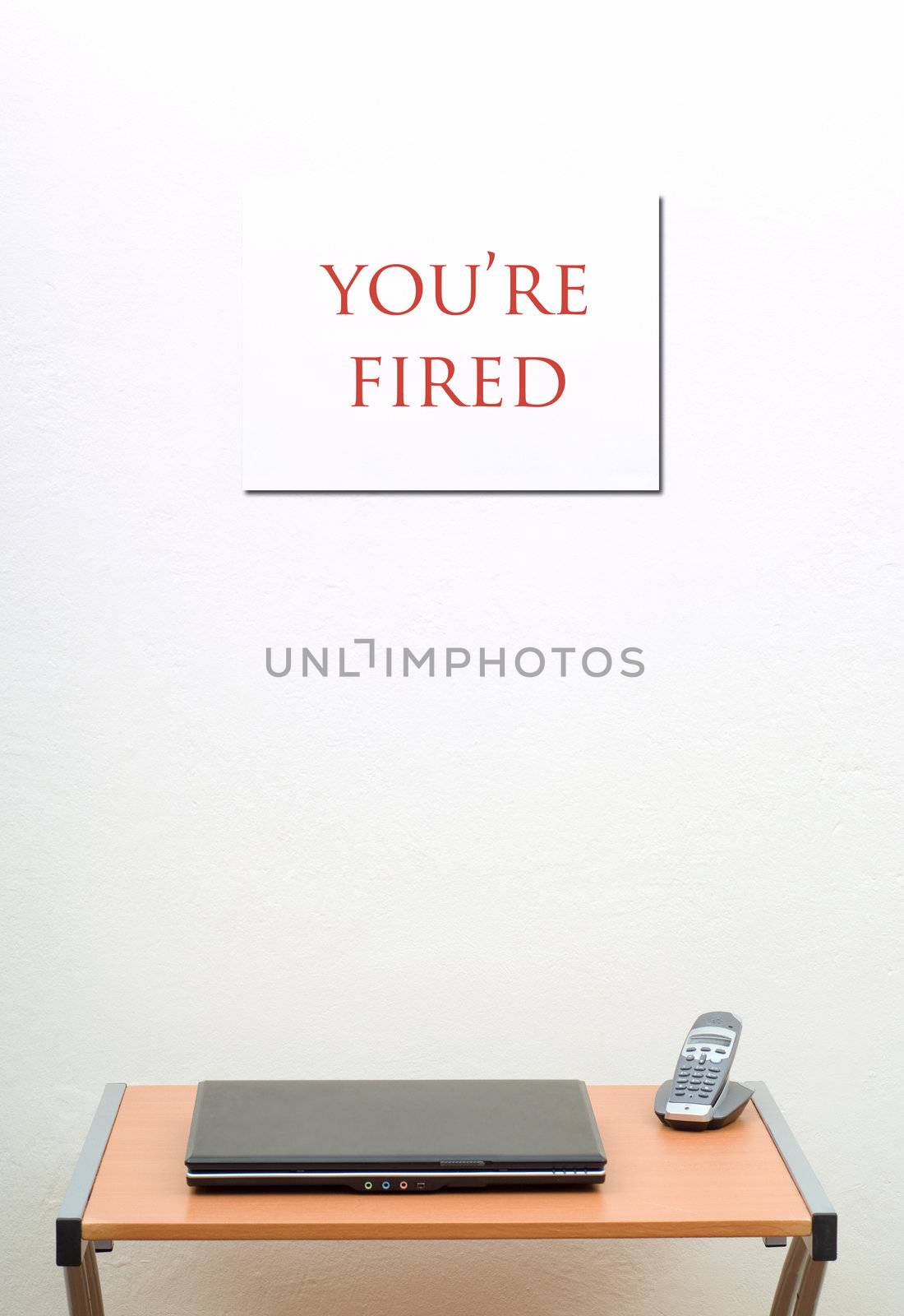 You're fired sign behind office desk with laptop and phone