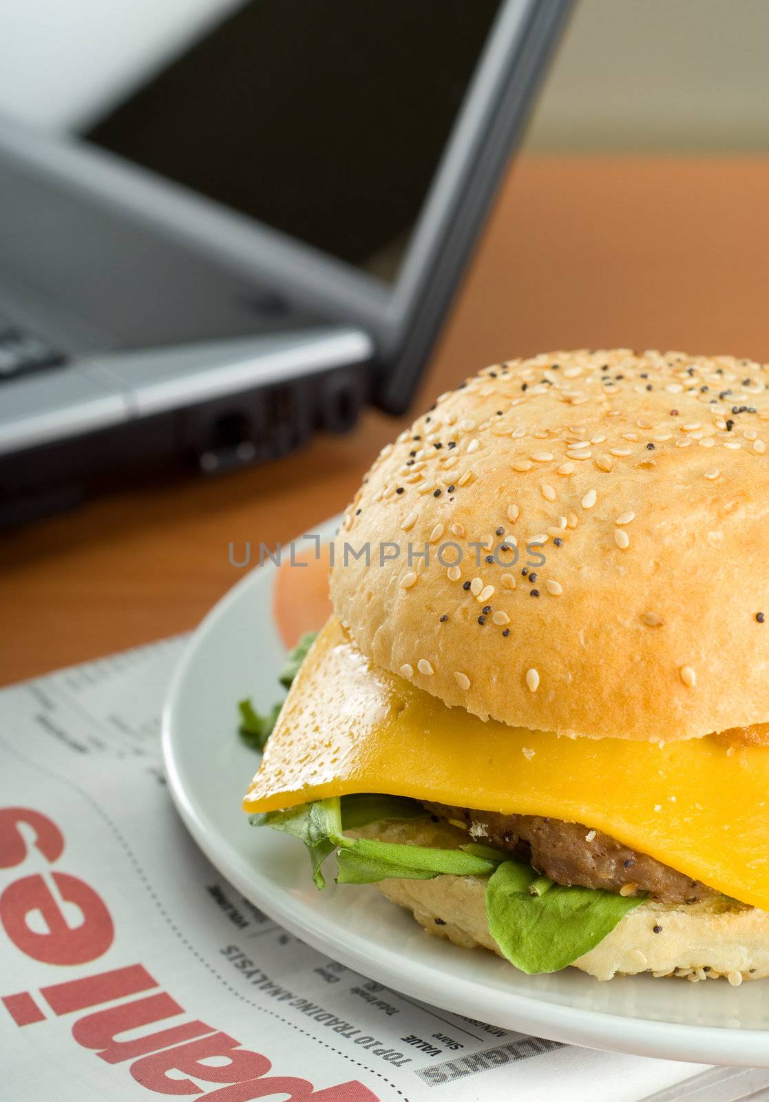 Office business lunch food cheese hamburger, laptop and financial newspaper on office desk