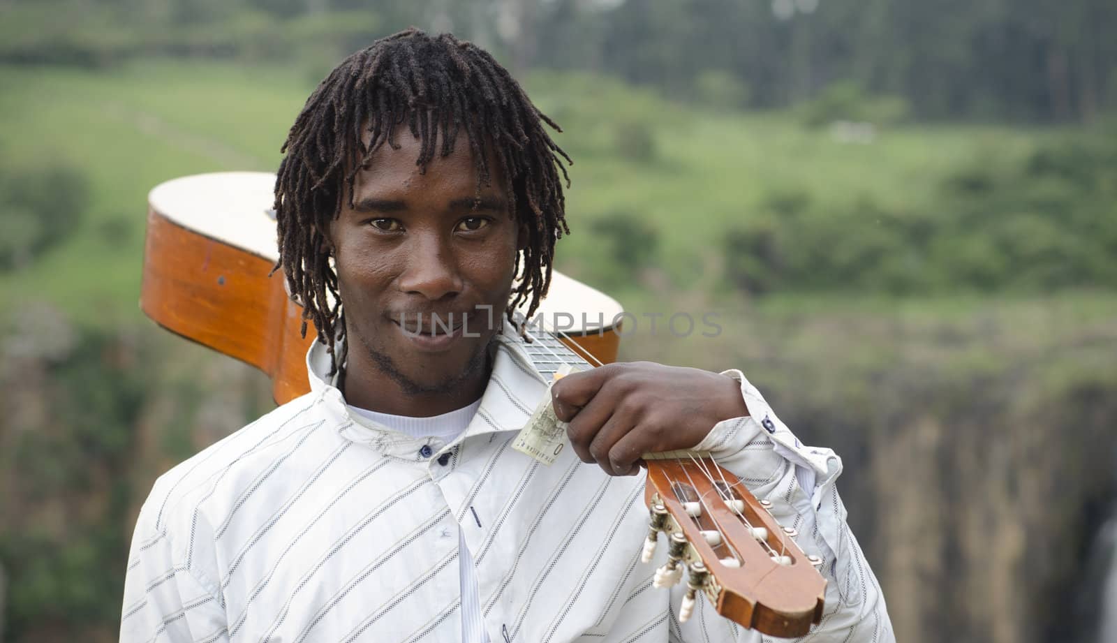 African busker with guitar on shoulder and ten rand note by alistaircotton