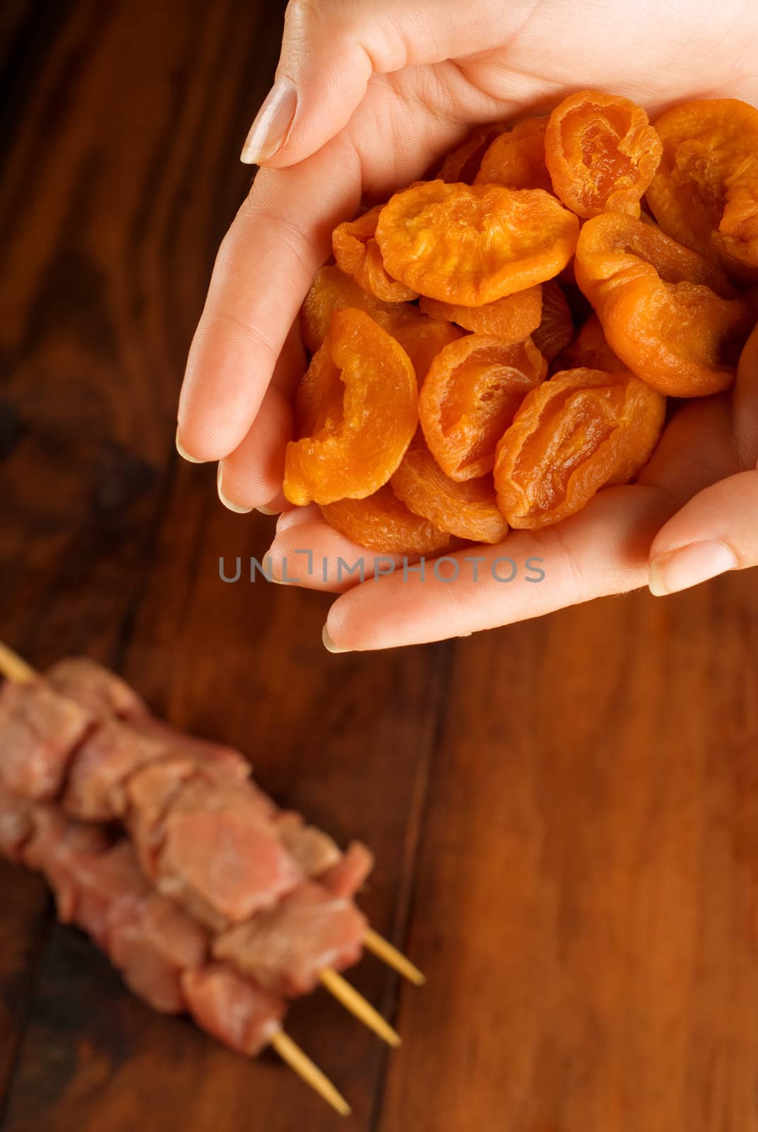 Chefs hands preparing beef skewer kebabs with apricots fruit