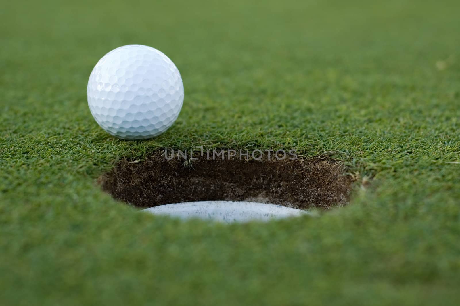 Golf ball on putting green next to hole