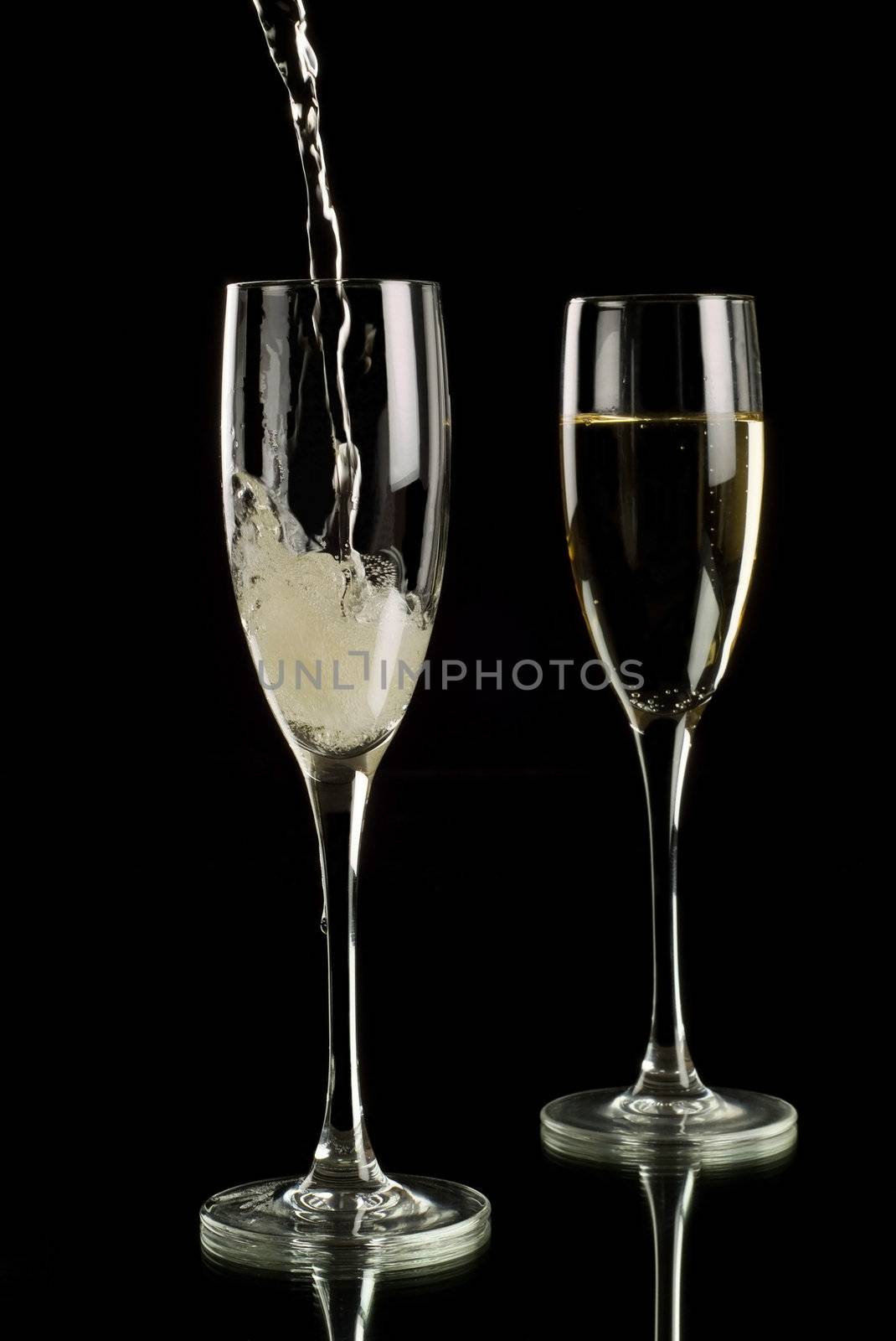 Sparkling wine poured into champagne flutes by alistaircotton