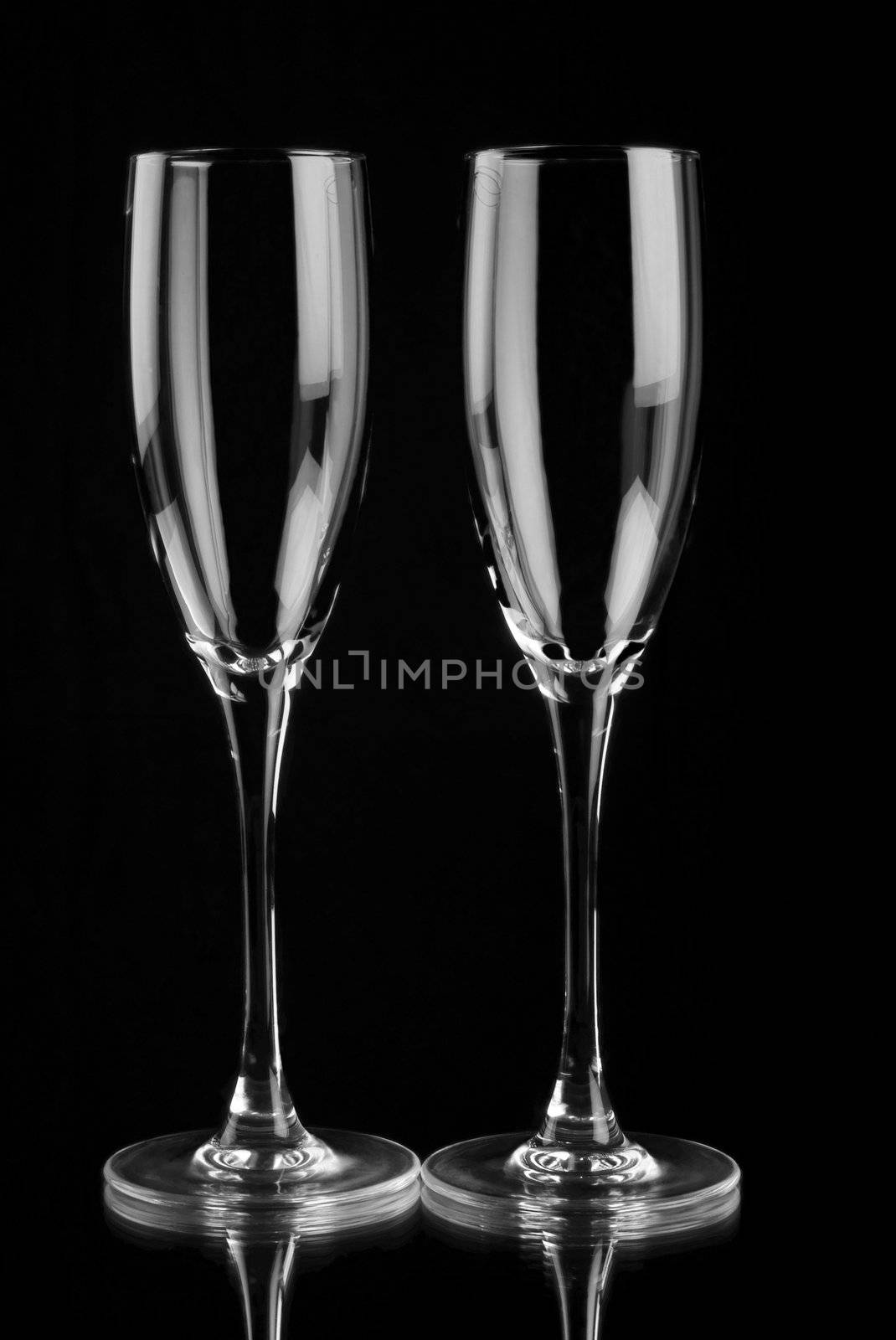Two empty champagne flutes with mirror reflection on black bacground
