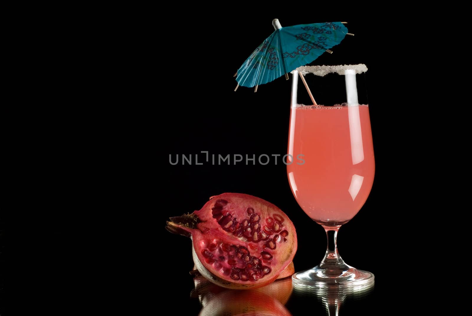 Brightly coloured cocktail drink with reflection and black background