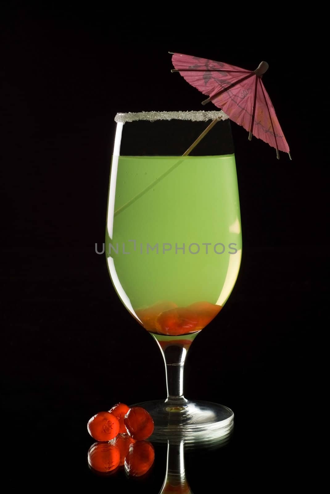 Brightly coloured cocktail drink with reflection and black background