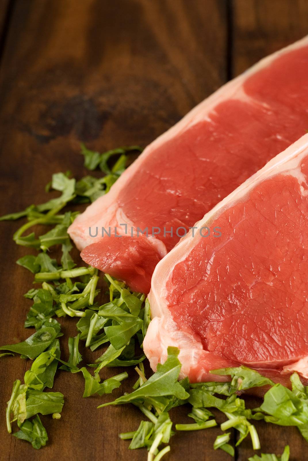 Fresh raw beef meat steak with herbs on wooden table or cutting board