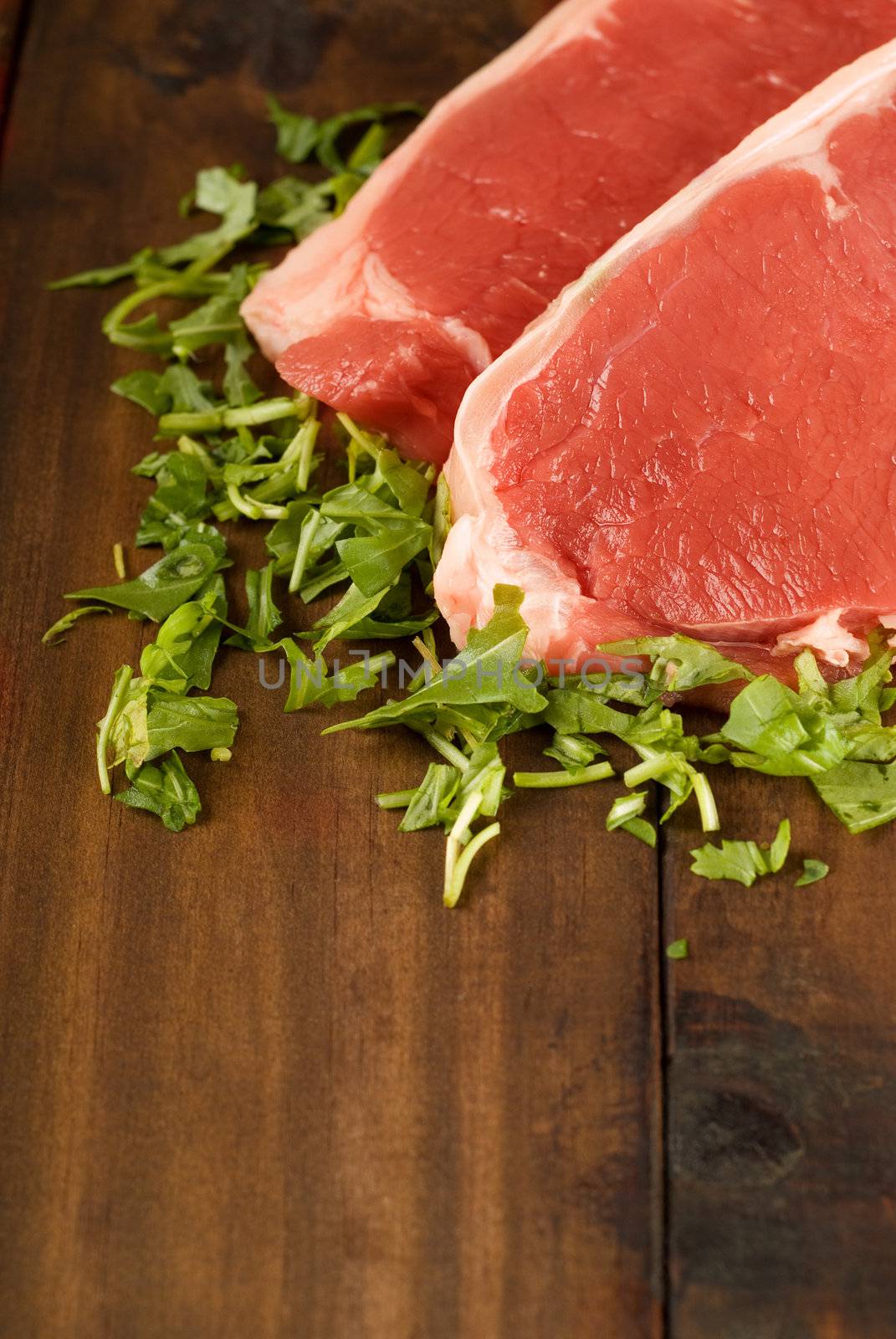 Fresh raw beef meat steak with herbs on wooden table or cutting board