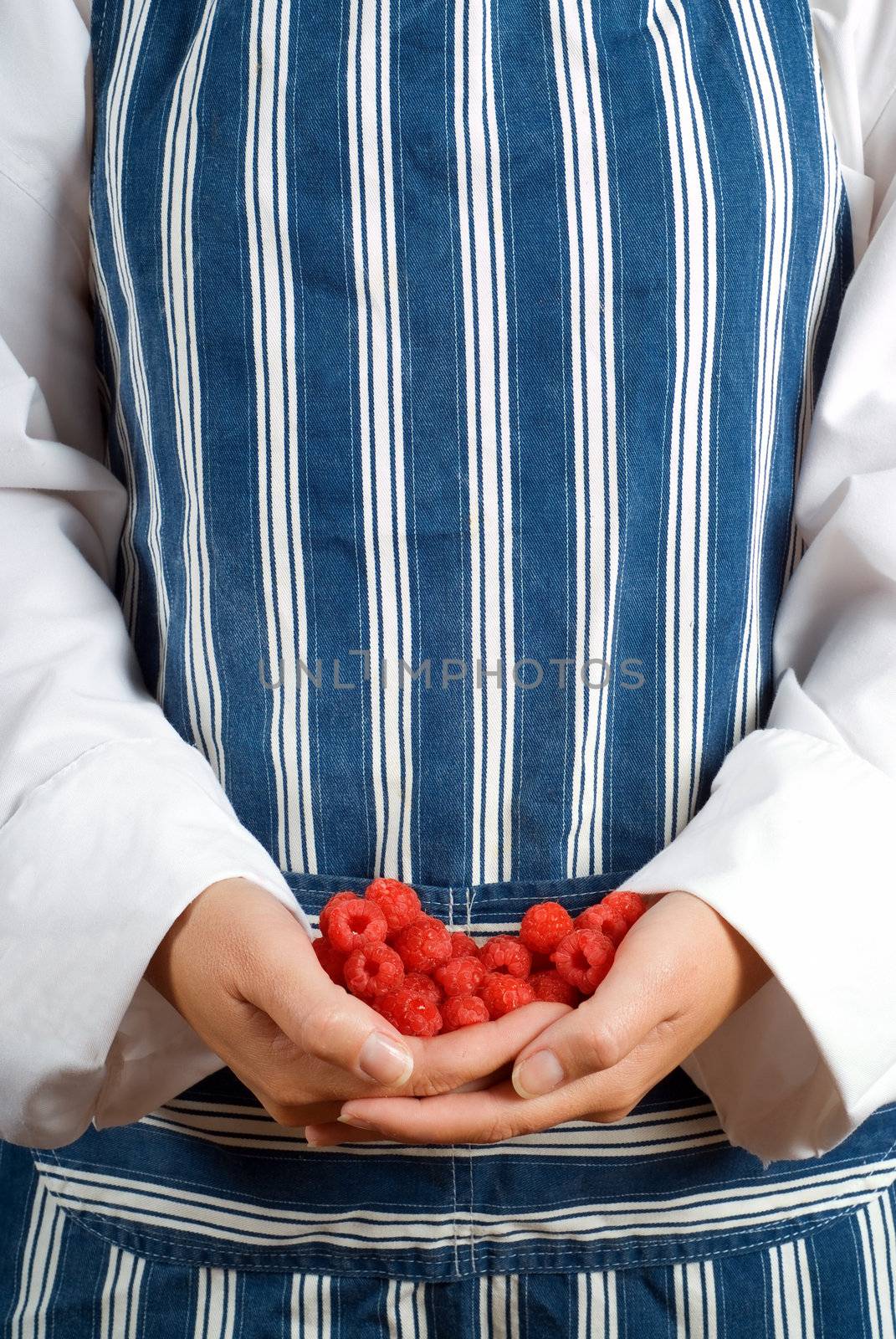 Woman cook or chef holding raspberries in her hands