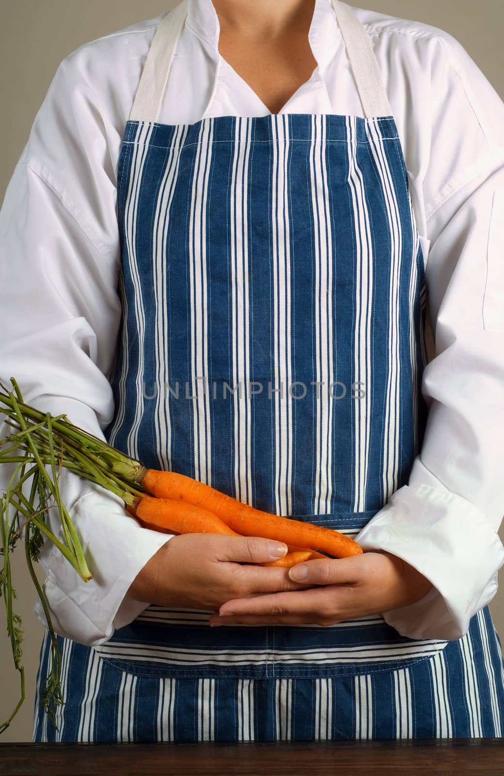 Woman chef or cook holding carrots in her hands