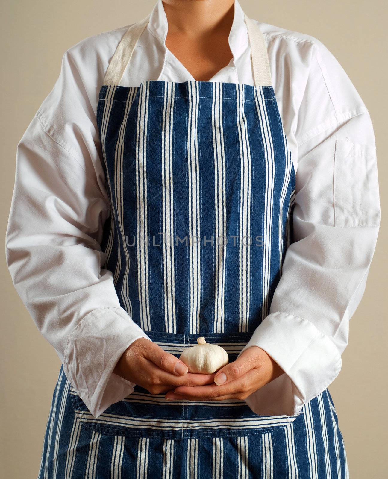 Woman chef or cook standing with garlic clove in hands