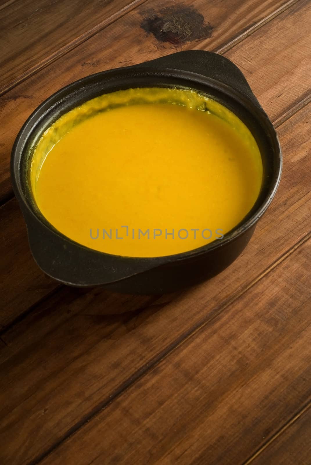 Butternut soup in black pot on wooden table