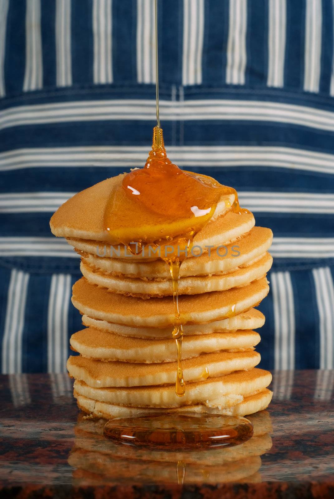 Chef or cook with striped apron pouring syrup on flapjacks or pancakes