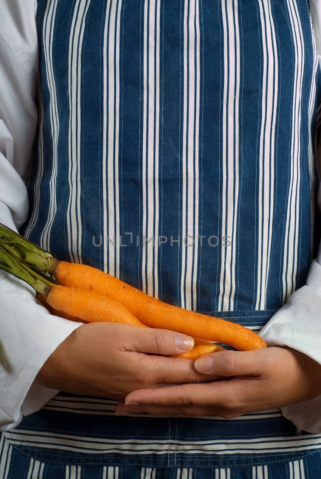 Woman chef or cook holding carrots in her hands