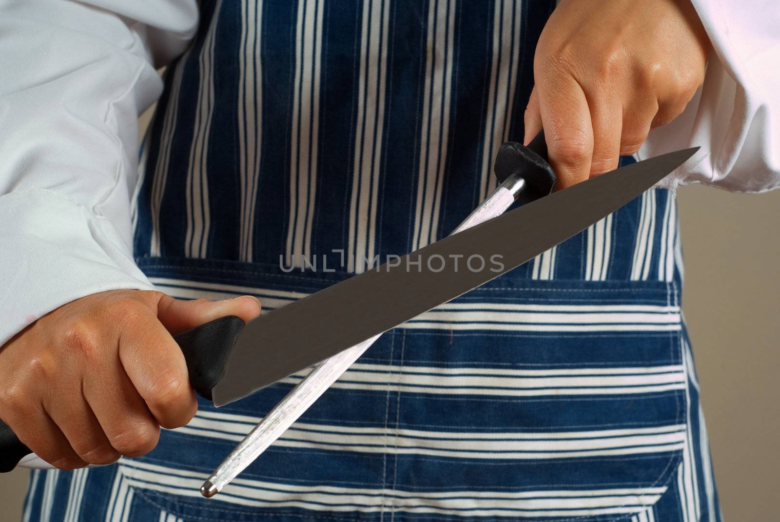 Woman chef or cook sharpening kitchen knife