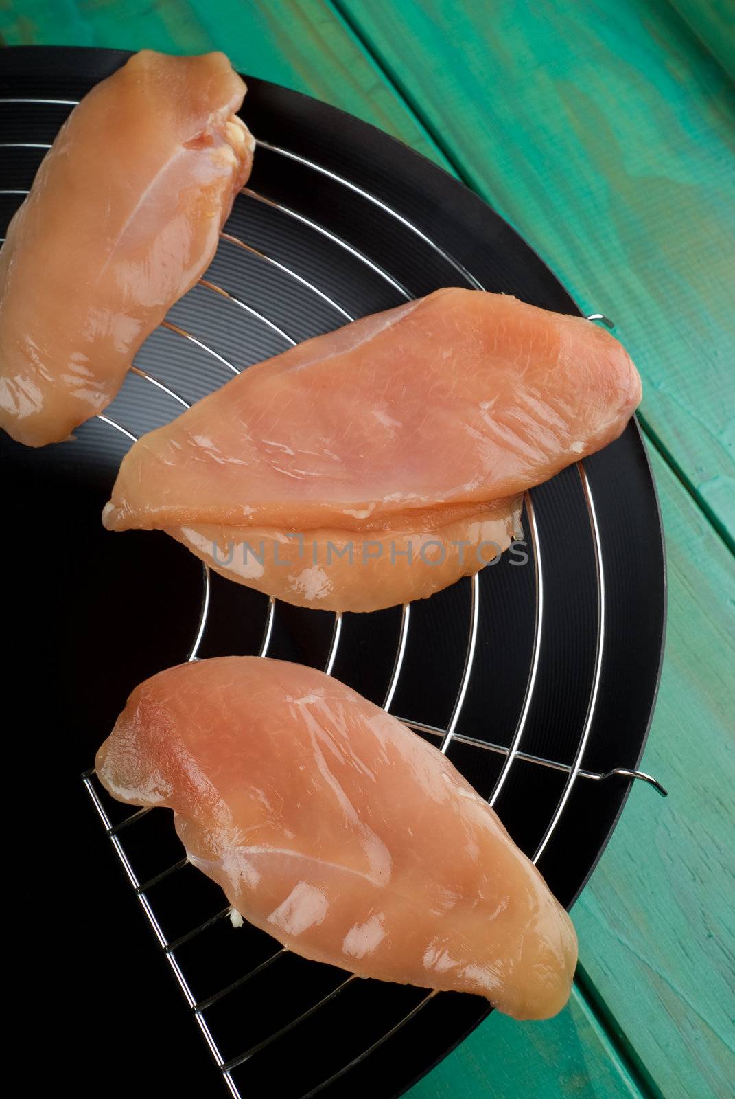 Raw chicken fillets on top of wok ready for stir fry