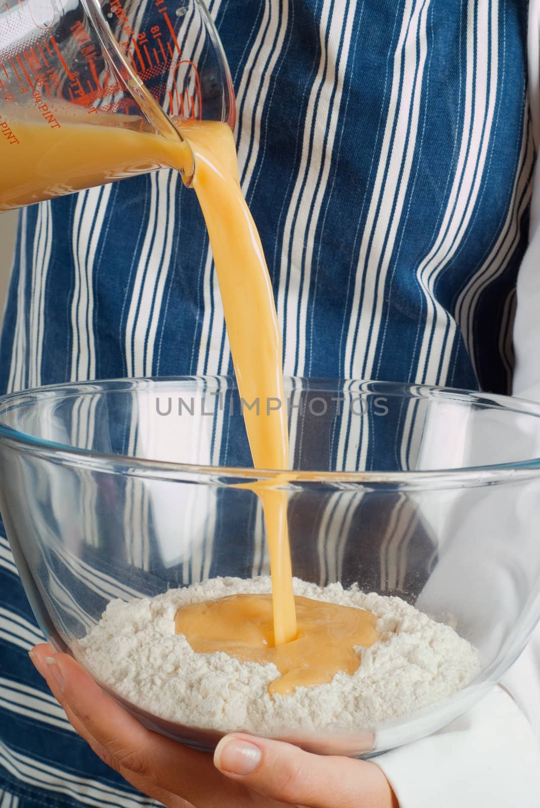 Woman chef cooking or baking and pouring pancake mixture batter into flour