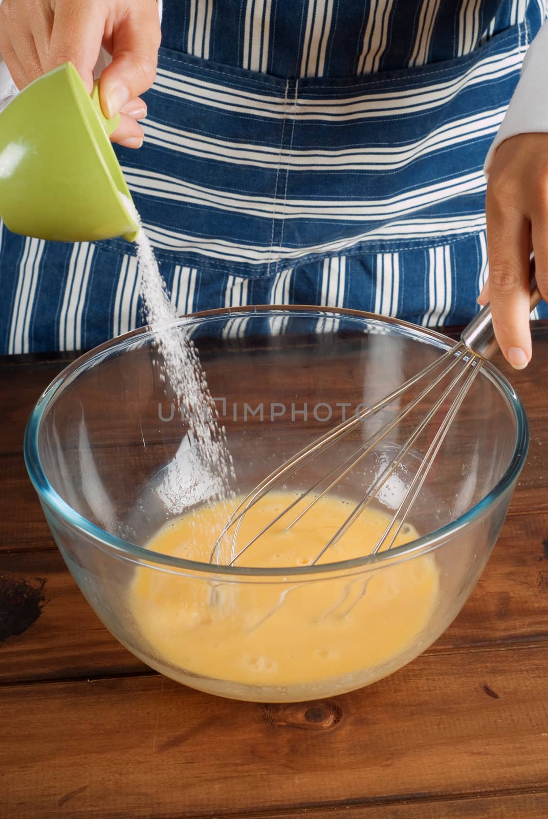 Woman chef cooking or baking and pouring sugar into pancake mixture batter