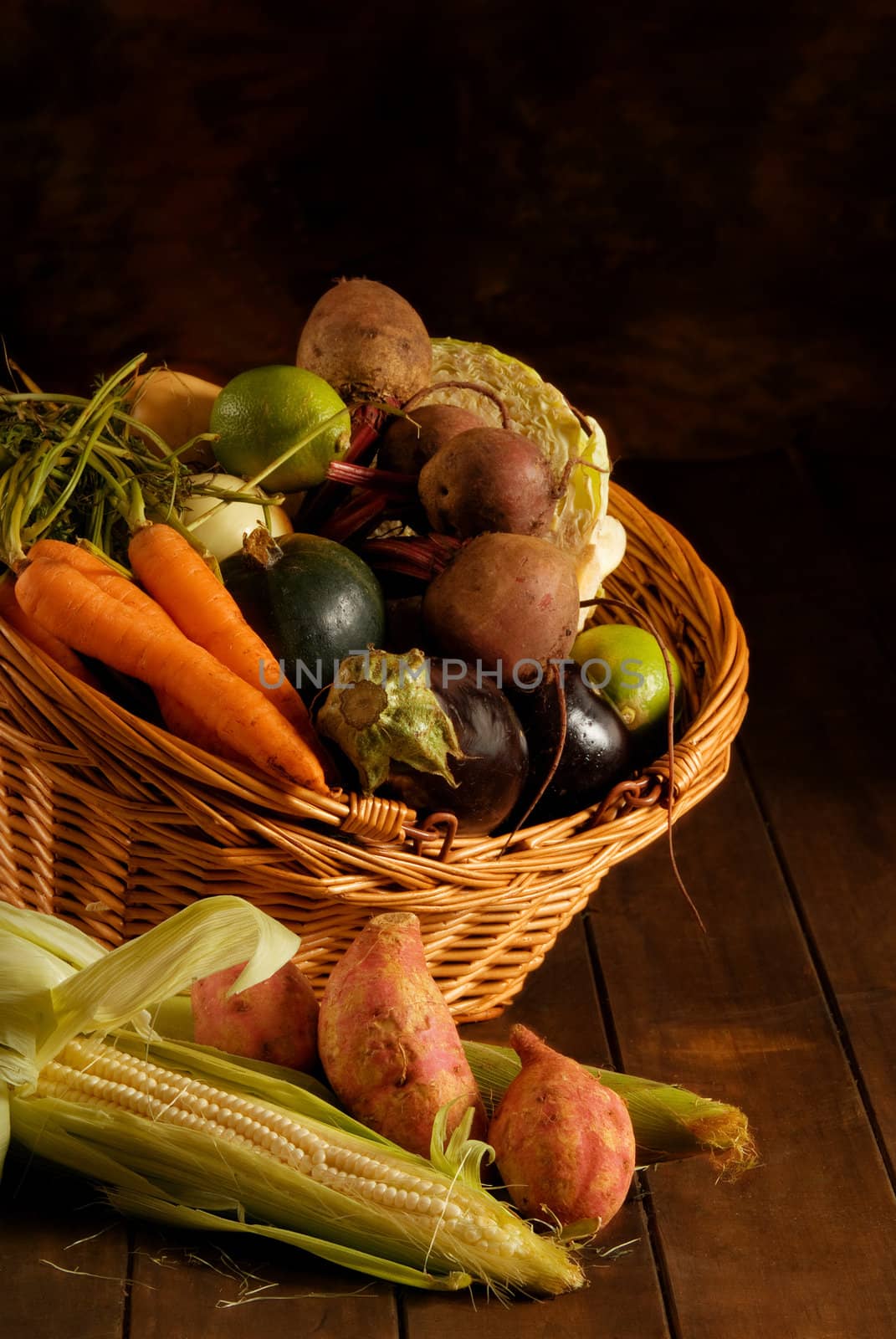 Thanksgiving basket filled with autumn fruits and vegetables on table with mottled background.