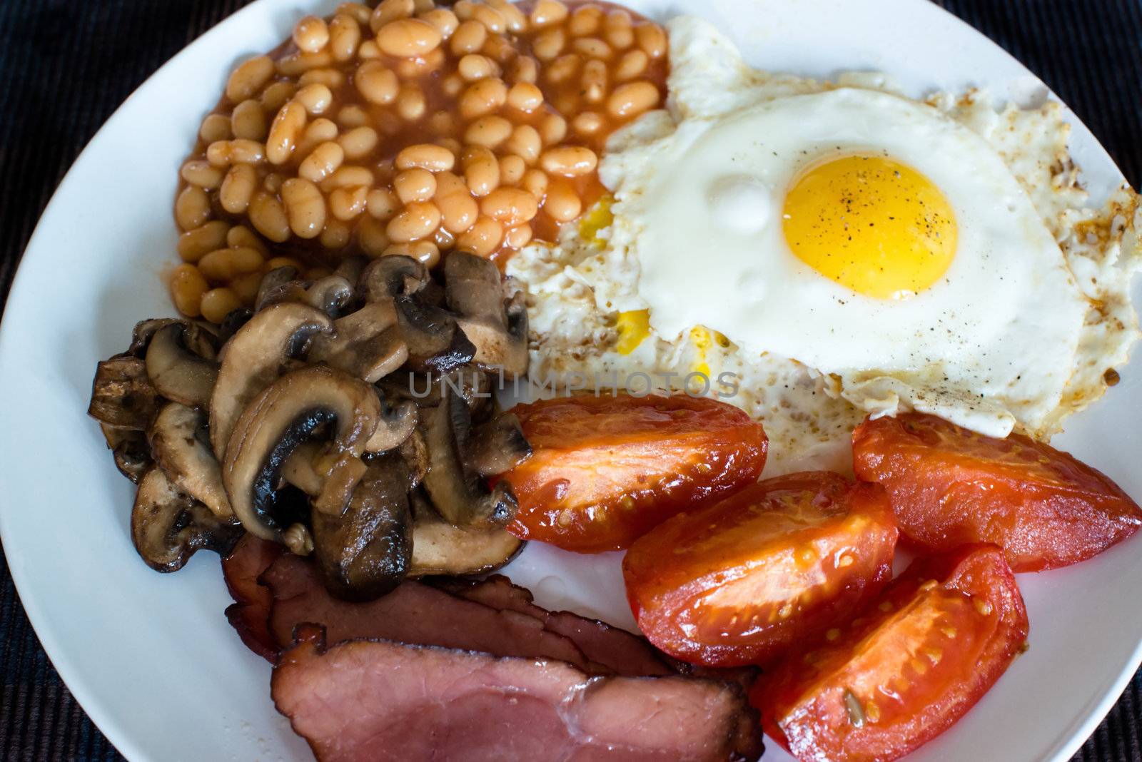 Traditional English breakfast - tomatoes, fried bacon, mushrooms, eggs and tomato baked beens