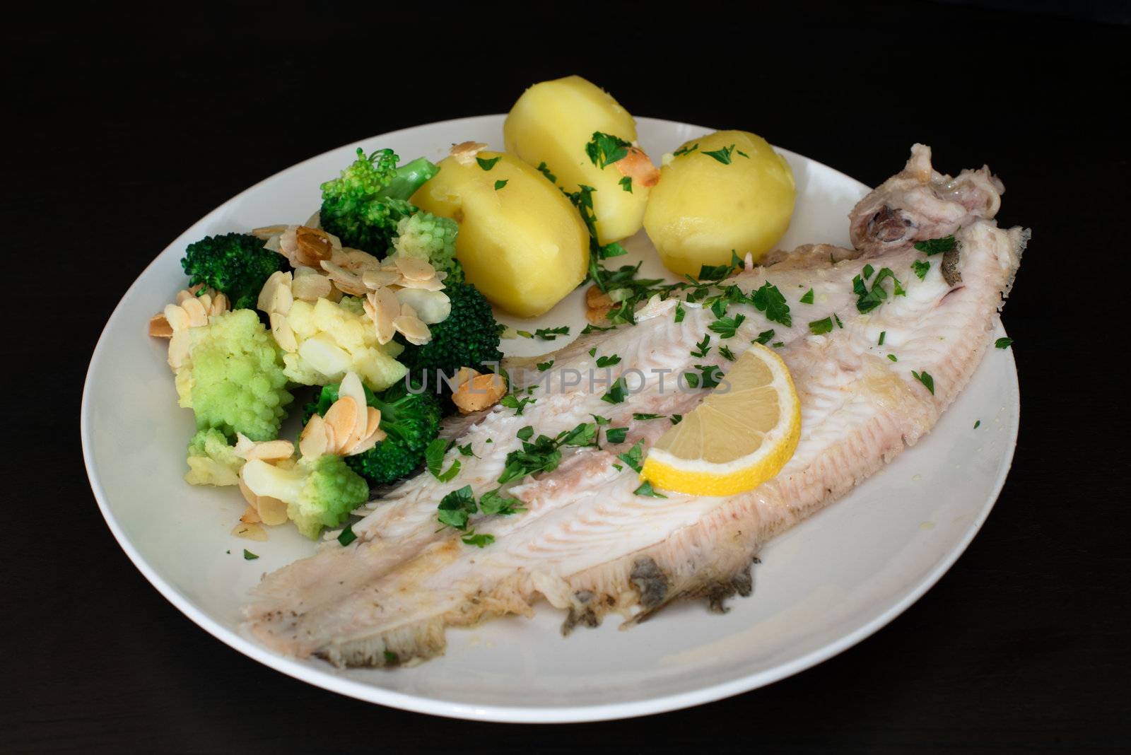 Dover sole fish dinner with potatoes, broccoli (romanesco and traditional), almond slices and lemon