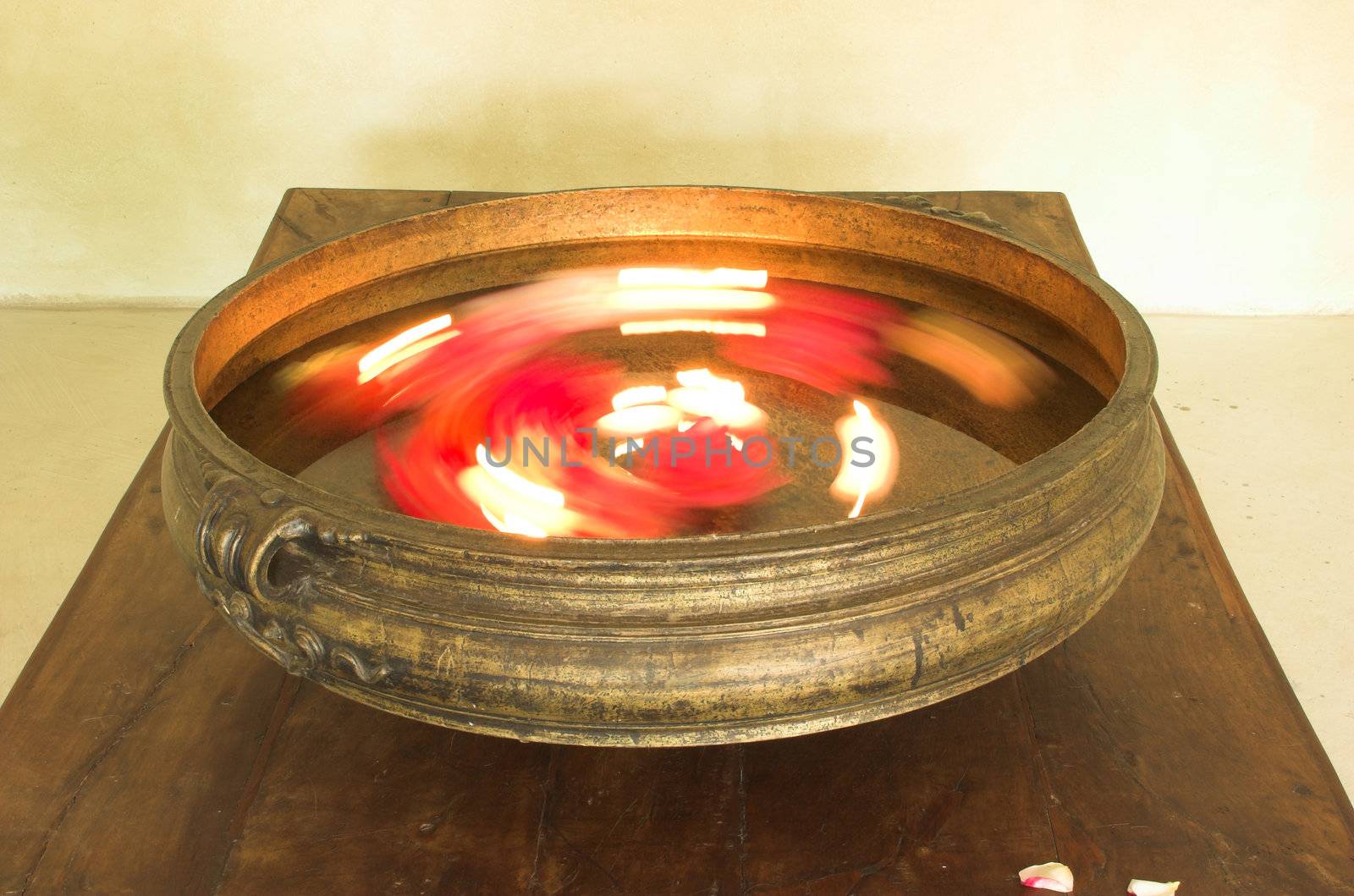 Traditional Indian urli brass bowl with blurred flowers and candles moving rotating inside