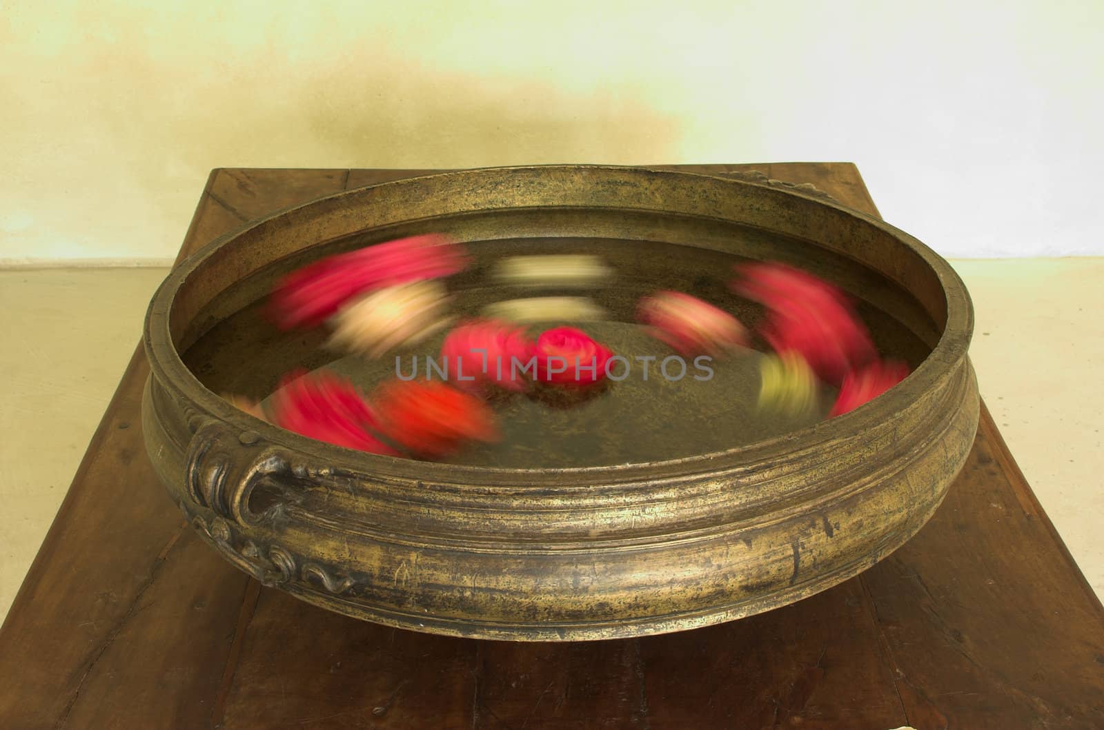 Traditional Indian urli brass bowl with blurred flowers moving rotating inside