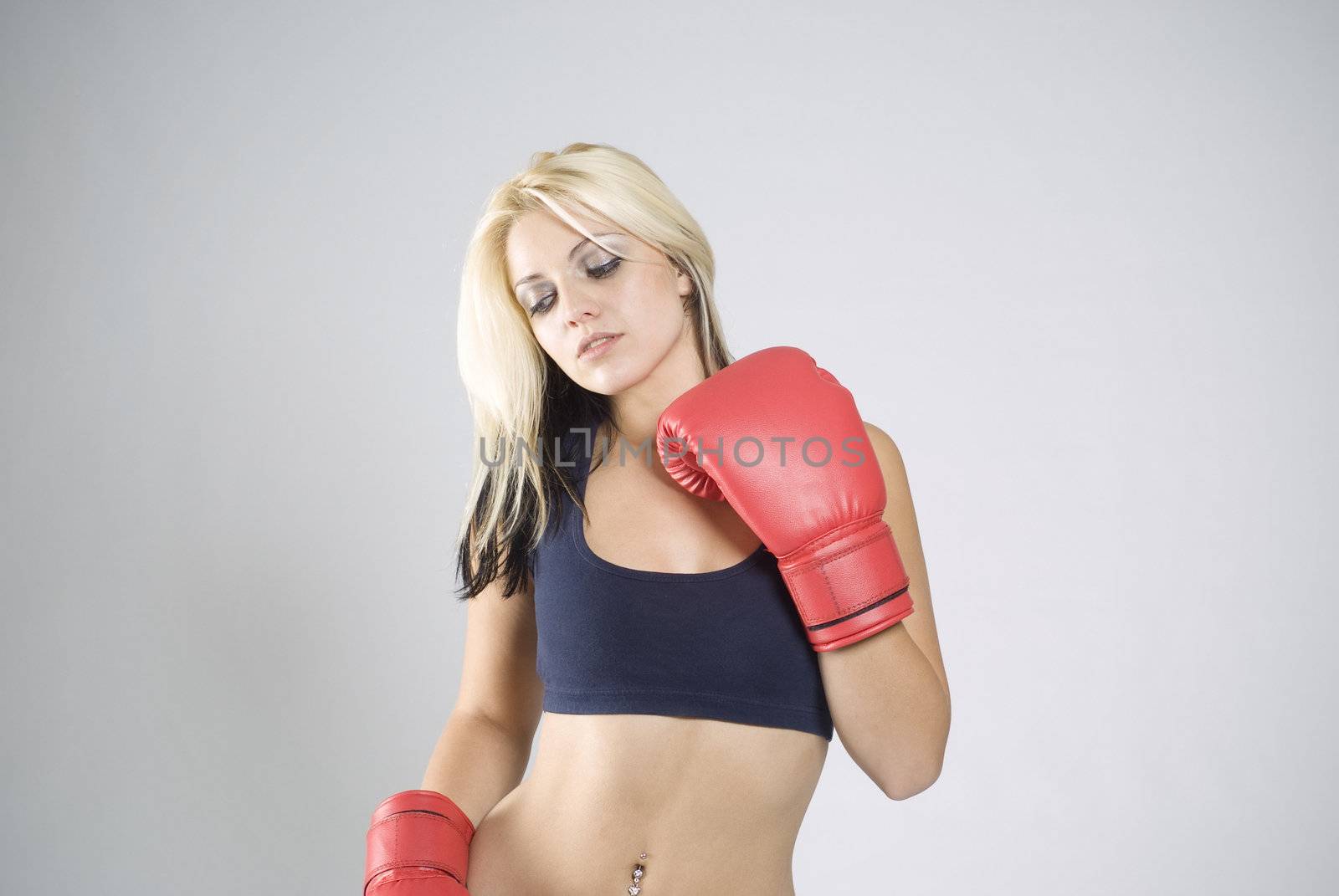 Elegant pose pretty fit blond woman boxer training or working out with red boxing gloves