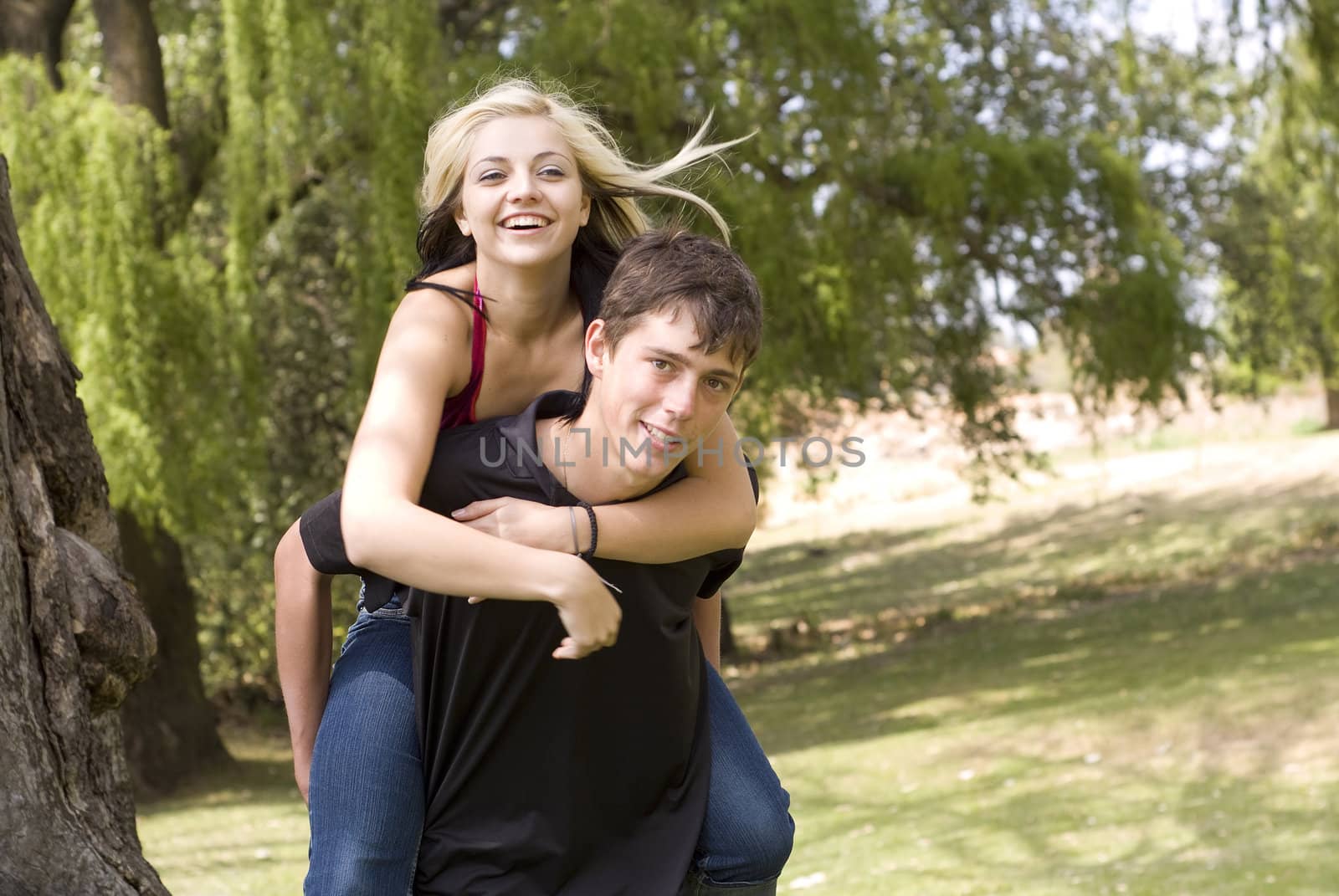 Happy girl on piggyback of boy friend in park