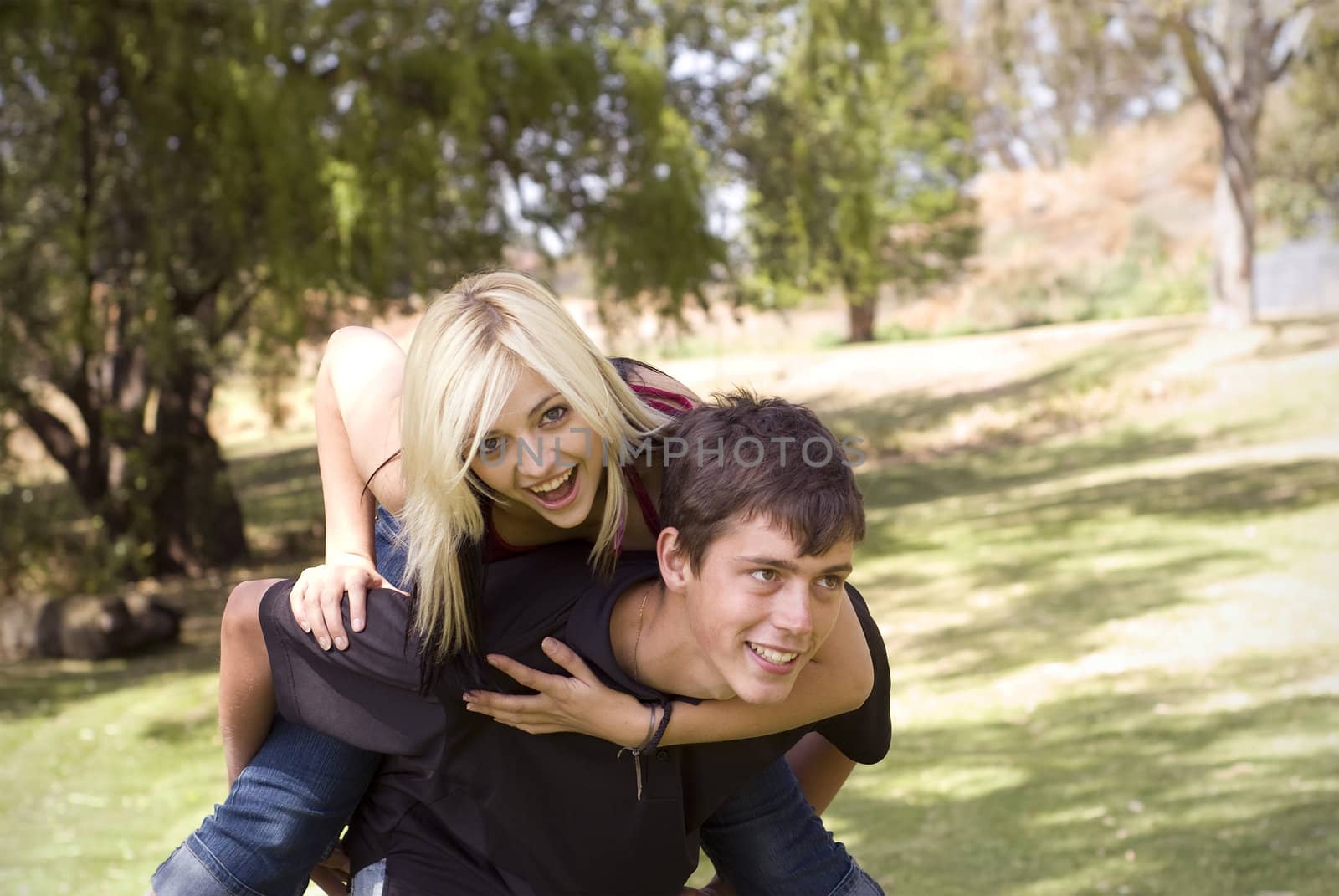 Piggyback girl on back in park with grass by alistaircotton