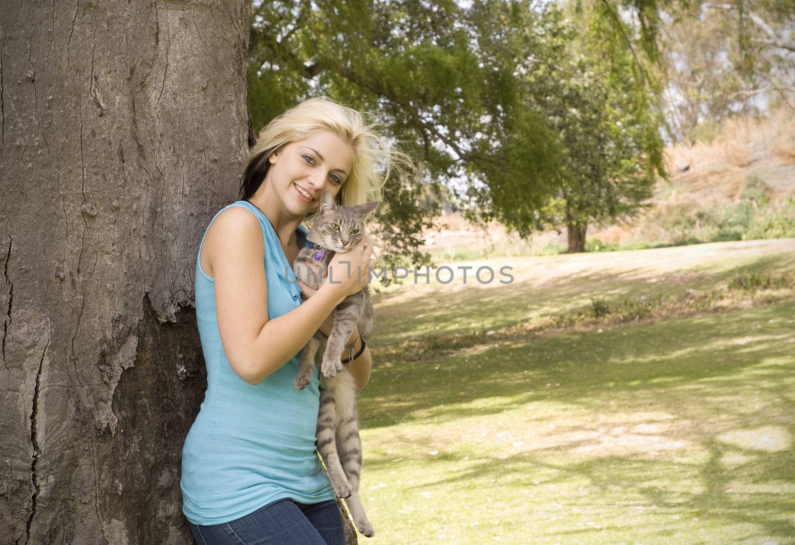 Woman or girl holding pet cat in garden