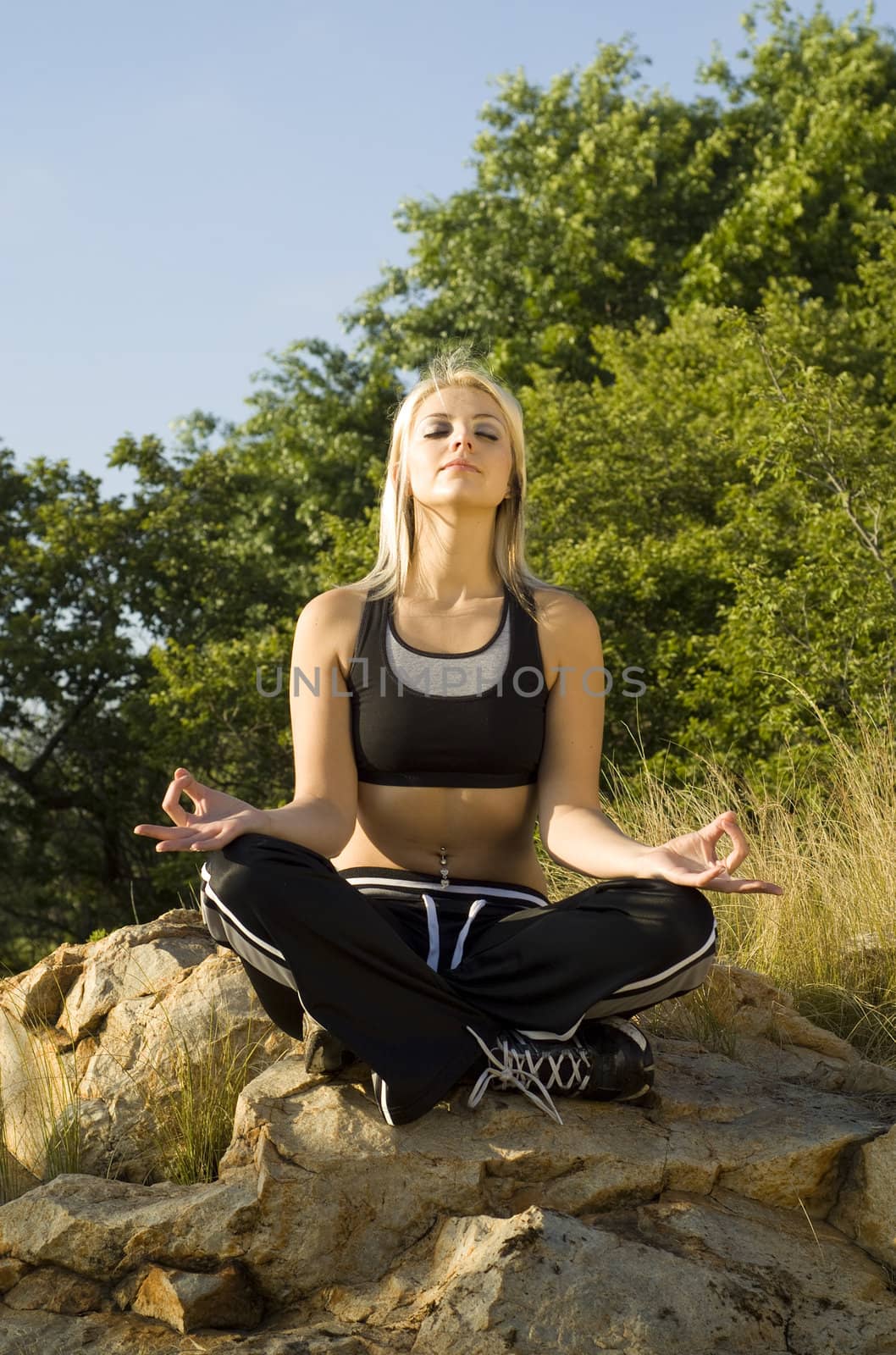 Portrait pretty woman meditating on rock lotus hands with gold light reflector